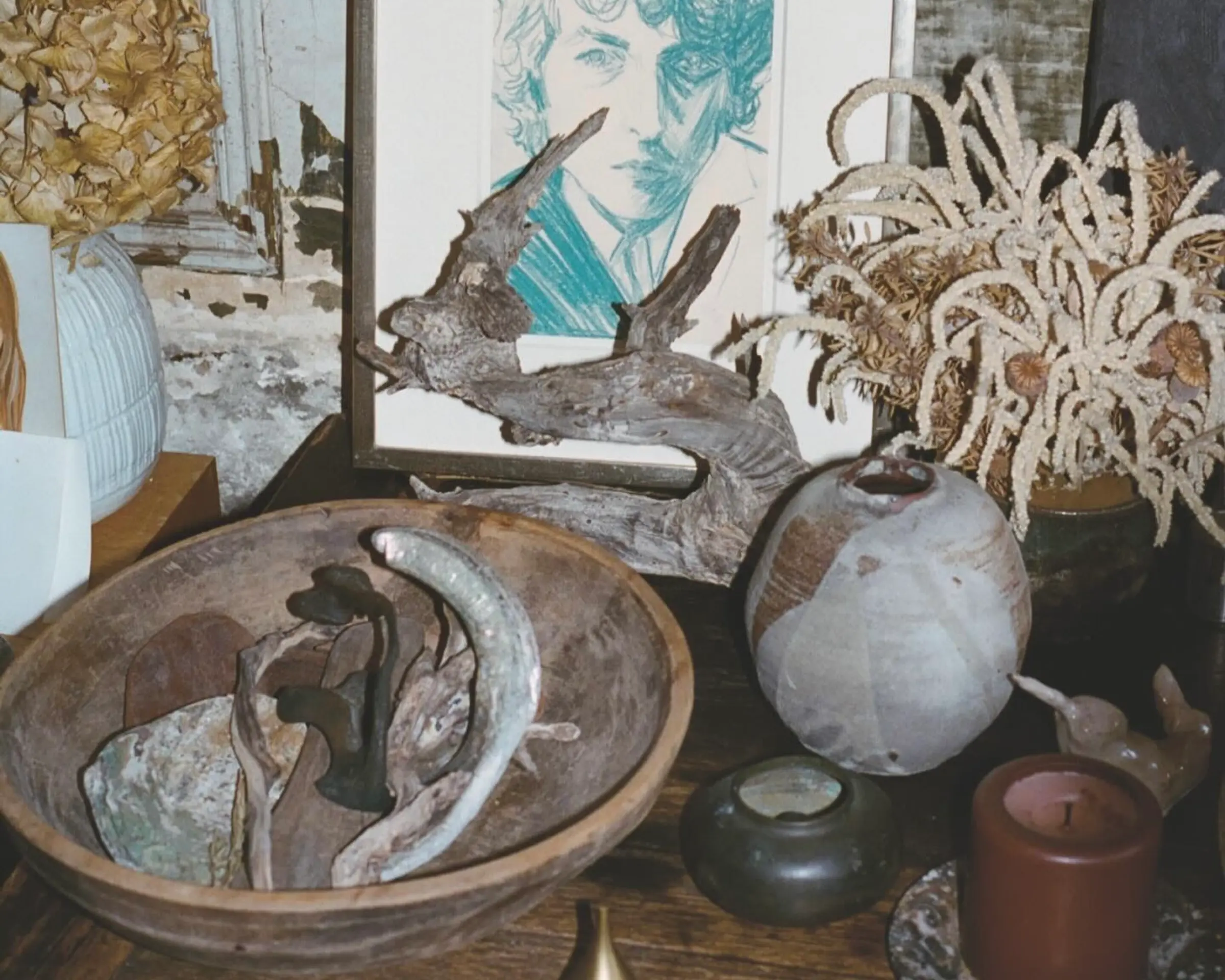 An image from Neptune papers issue 9 of a side table filled with collected decor, a sketch of a man, a ceramic vase, wooden bowl with various objects inside