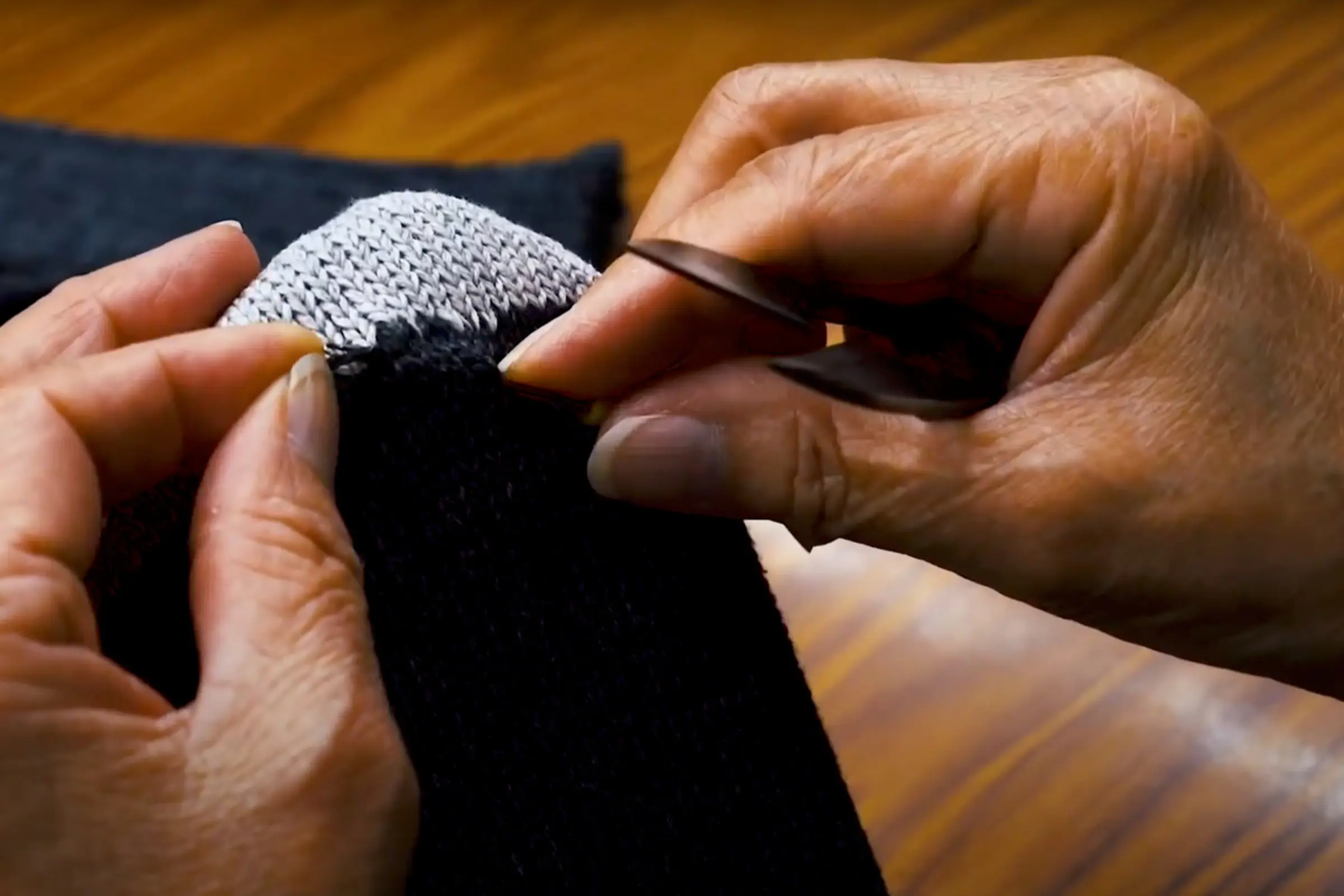 a close up of a worker quality controlling and pair of socks and knitting all the loose threads in