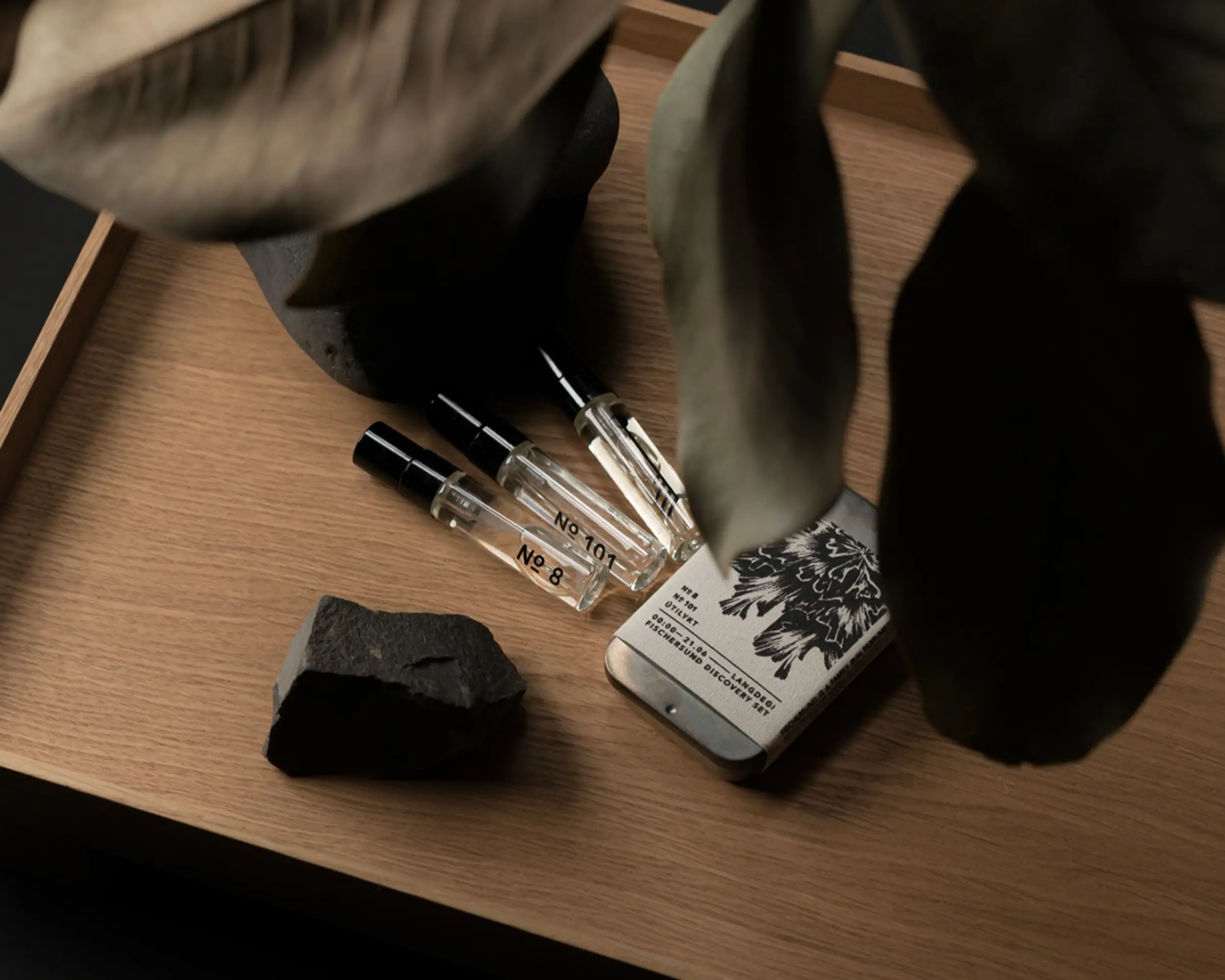 light perfume discovers spray kit on a wooden table with leaves hanging over