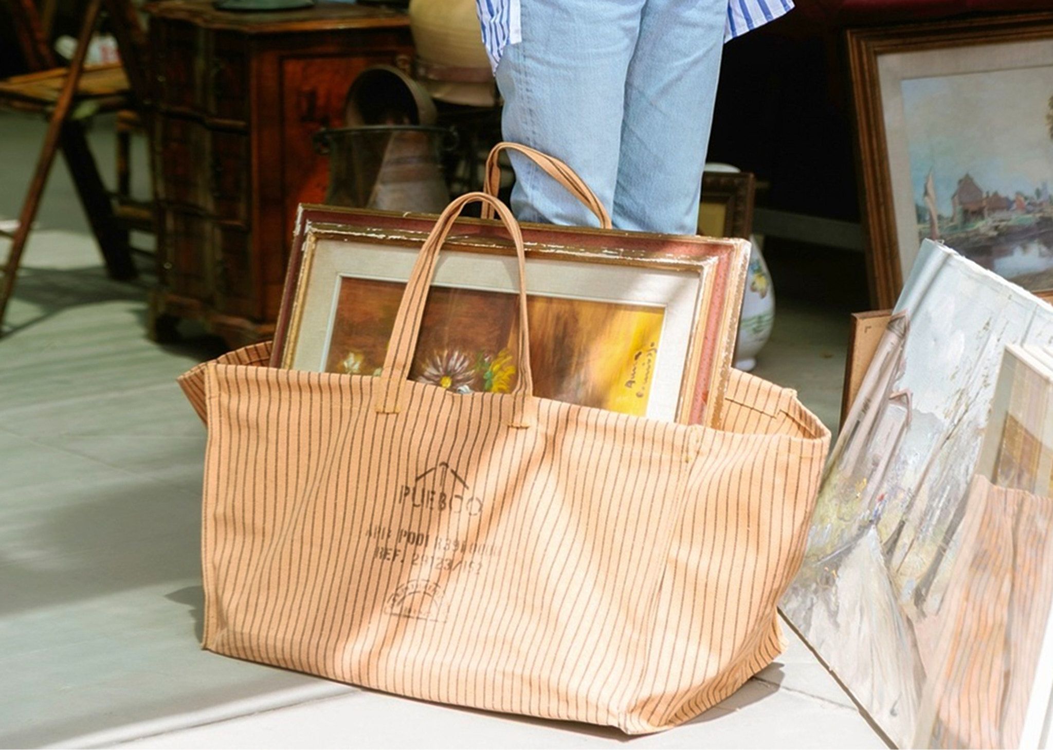 Puebco Waxed Canvas Large Bag in a market setting, carrying framed artwork and vintage finds, crafted from durable waxed cotton with utility-inspired detailing, available at Handcrafted Modern.