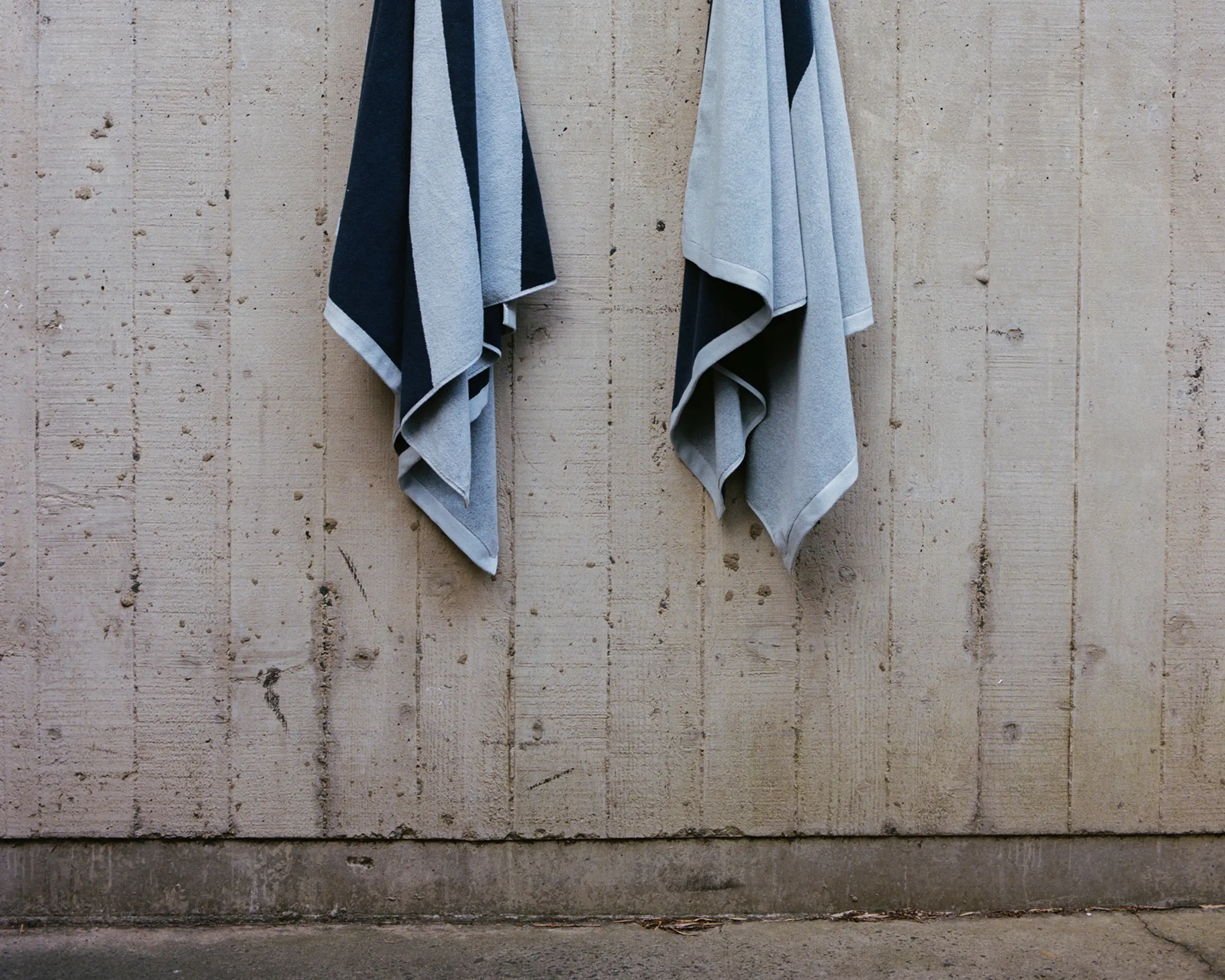 Two towels hanging on hooks on a wooden wall