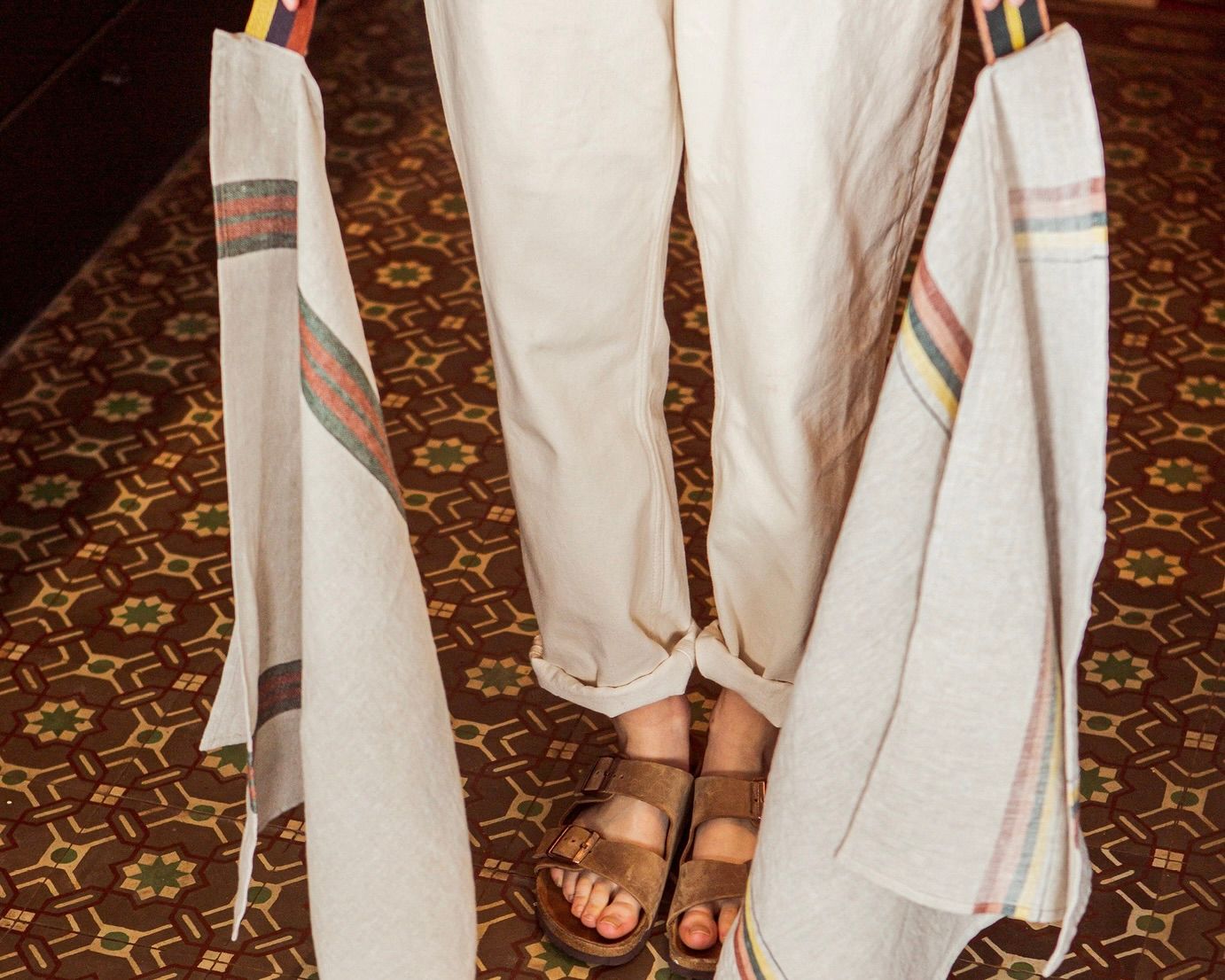 Libeco 100% linen Belgian woven tea towels with stripe detailing being held by a woman with patterned carpet underneath 
