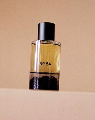 An image of Fischersunds fragrance No. 45, in a hand blown glass bottle with an inverted design showing the Icelandic terrain. The perfume sits on a beige plinth and background