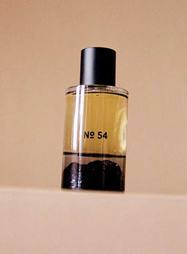 An image of Fischersunds fragrance No. 45, in a hand blown glass bottle with an inverted design showing the Icelandic terrain. The perfume sits on a beige plinth and background