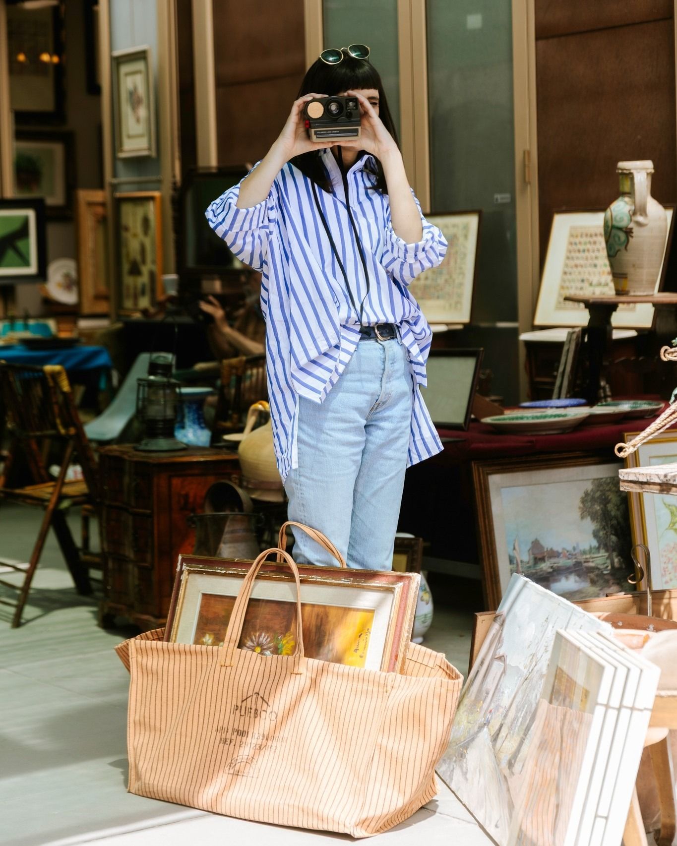 a lady in a market with a Puebco waxed canvas tote bag holding a painting
