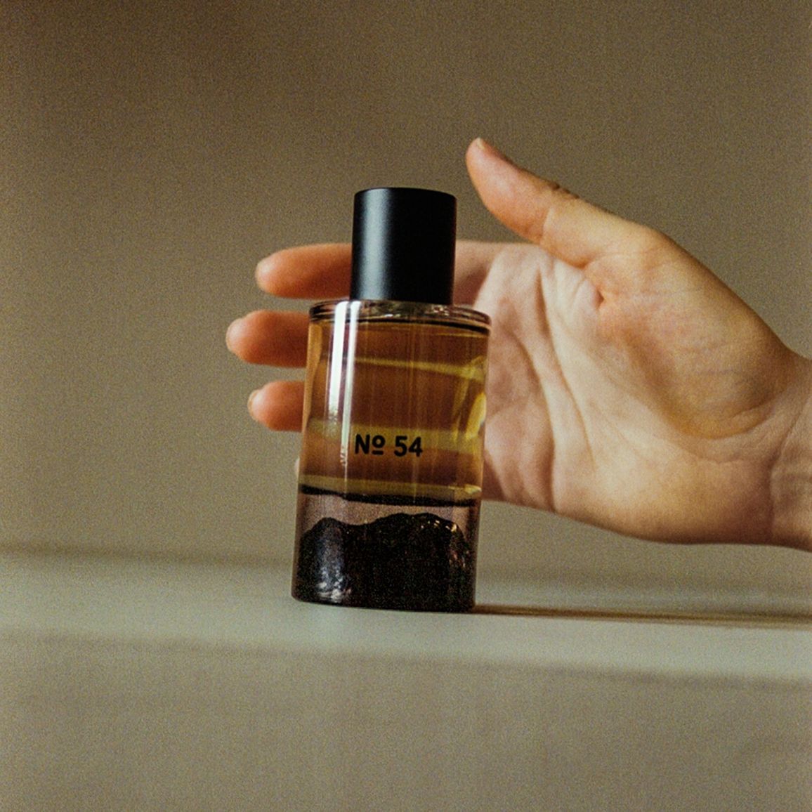 Hand holding Fischersund Fragrance No. 54 perfume, handcrafted in Reykjavík and featuring bergamot, mountain pine, cedarwood, leather and vetiver notes, available at Handcrafted Modern.