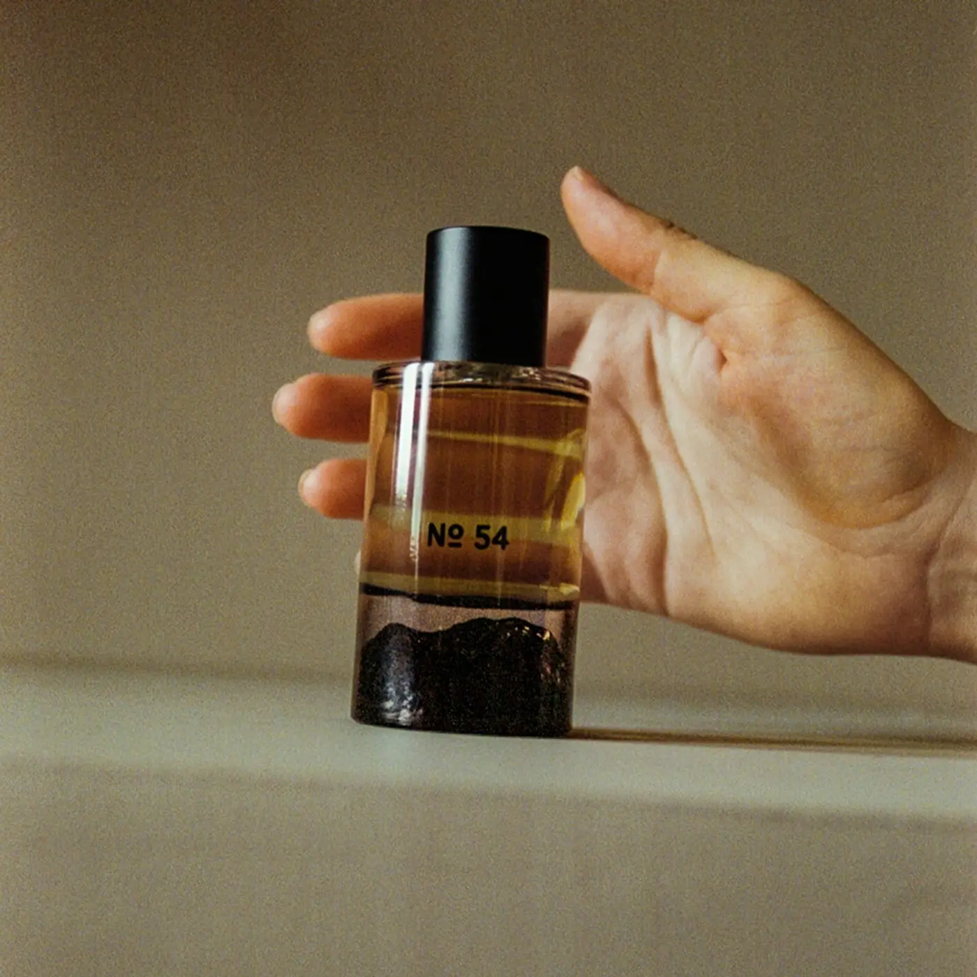 Hand holding Fischersund Fragrance No. 54 perfume, handcrafted in Reykjavík and featuring bergamot, mountain pine, cedarwood, leather and vetiver notes, available at Handcrafted Modern.