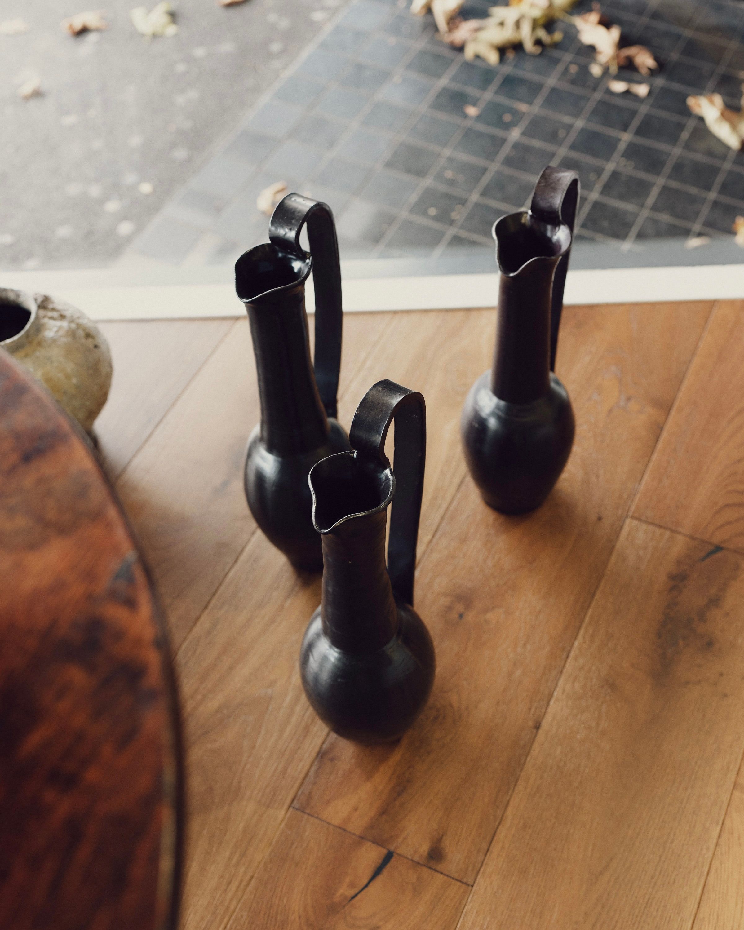 3 Olpe Tall handled vases with a deep chocolate vase on wooden floorboards in a shop window
