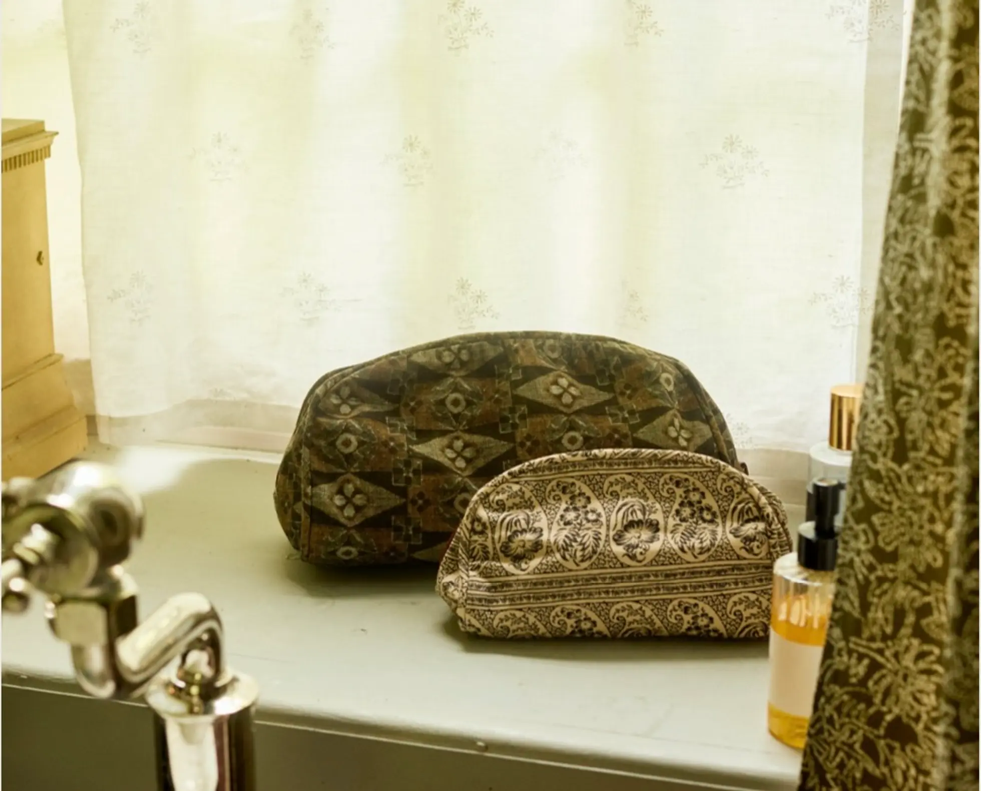 Printed toiletry bags on a dappled light bathroom windowsill