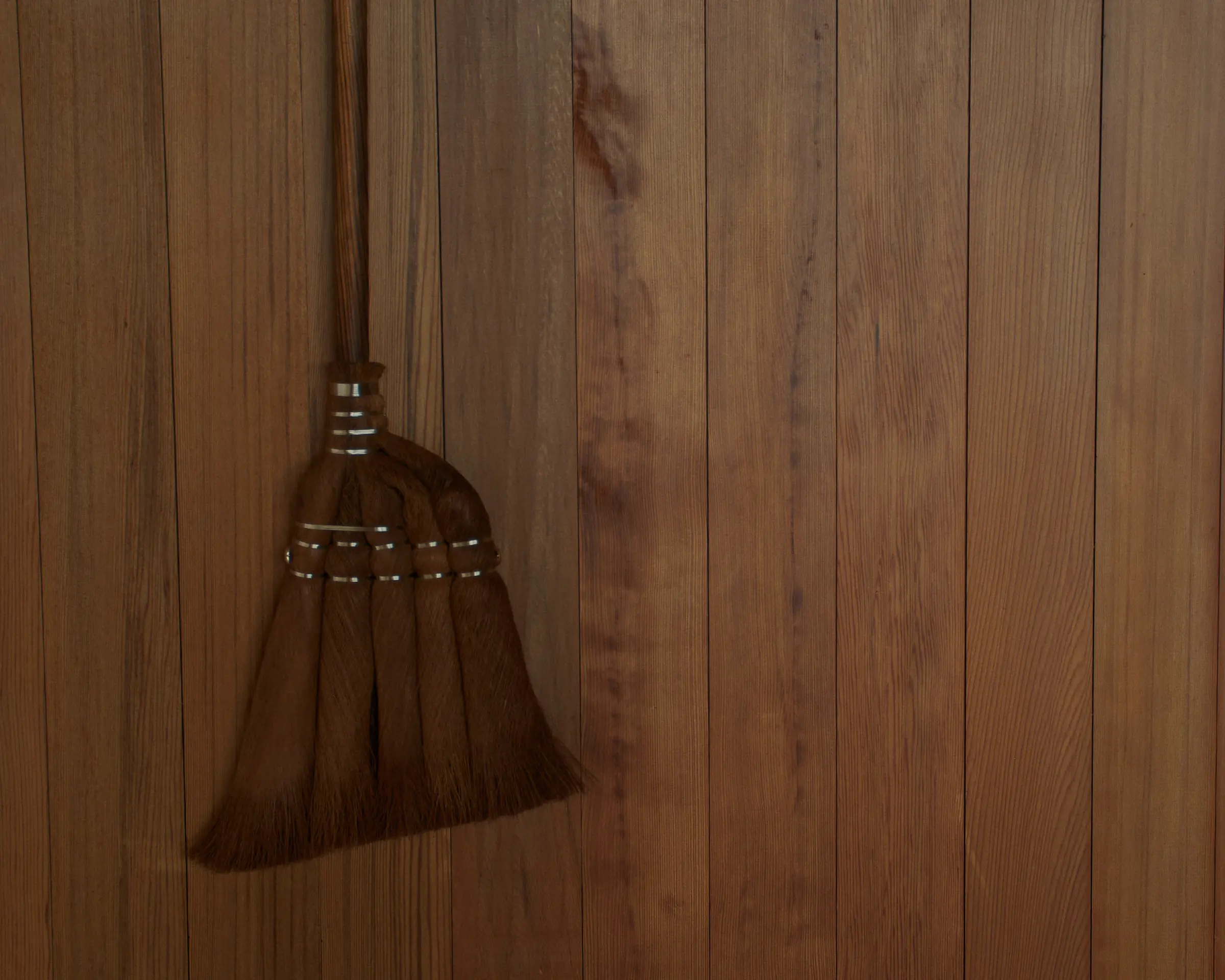 Japanese cypress broom hanging on a wooden wall