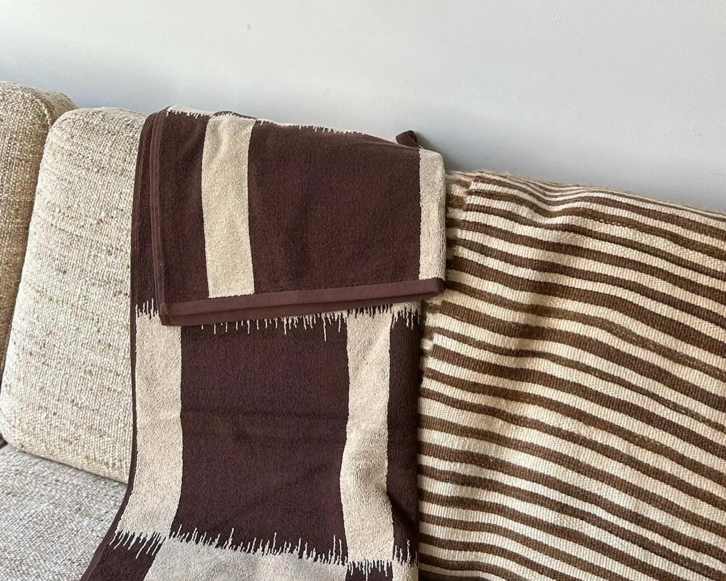 Karin Bath Towel draped on a cream sofa