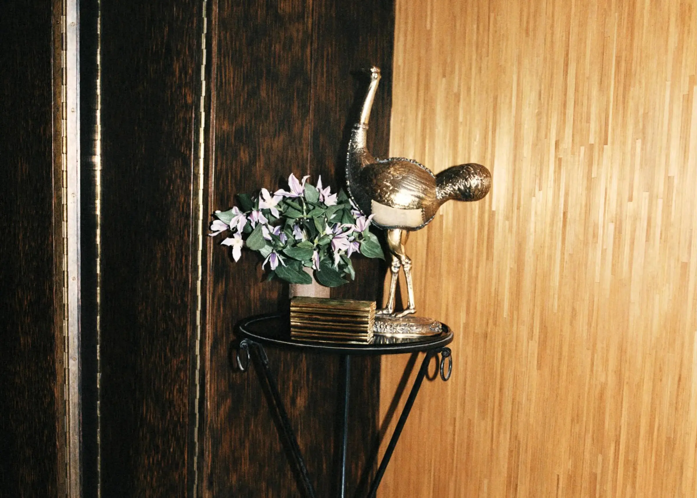 An image from inside Neptune papers latest magazine, a corner of a home with a side table and metallic sculpture with wooden walls behind