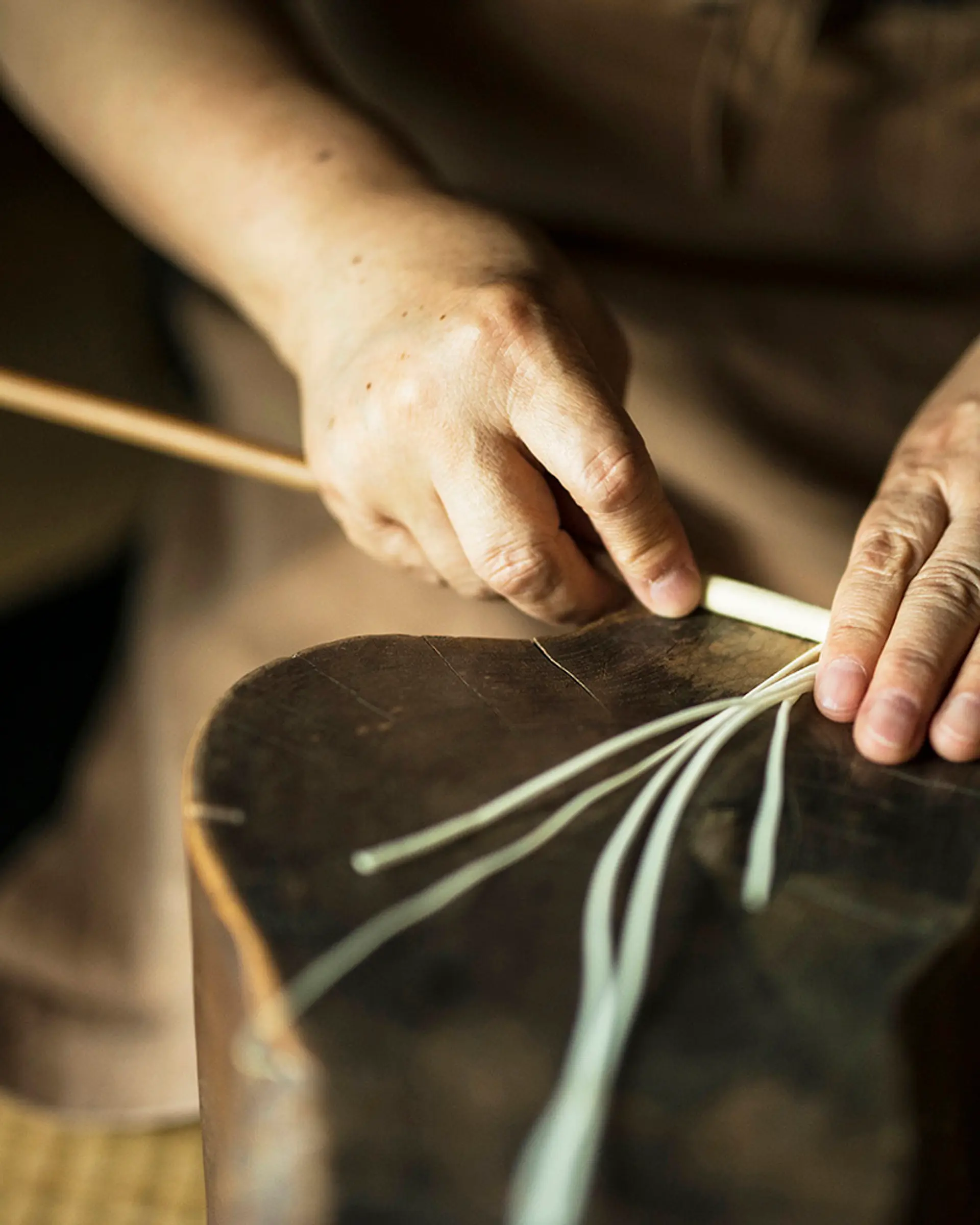 Hand wrapping silk around a stick before sumac is dipped to make candles