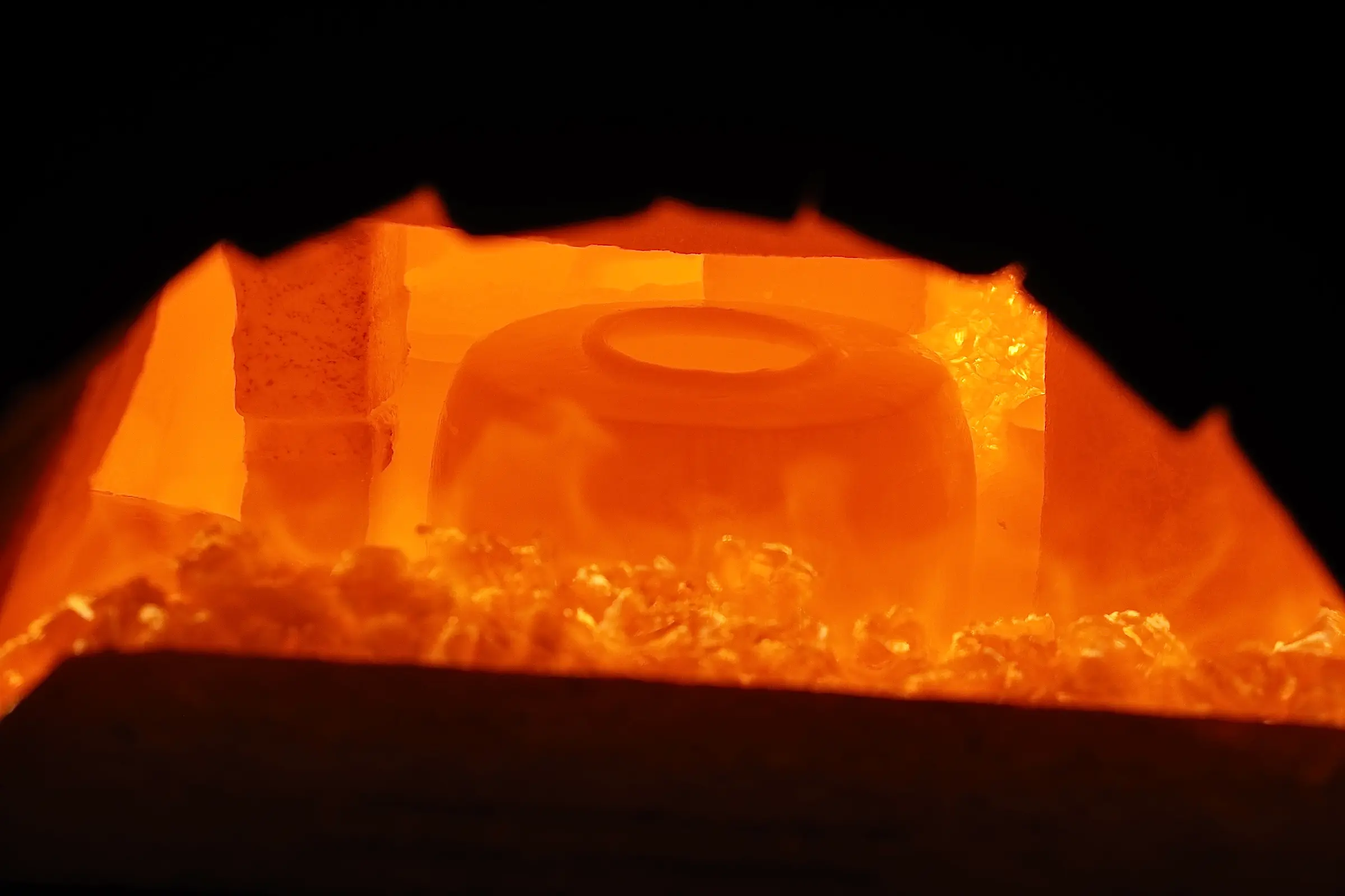 An image of Holly rose Morgans ceramic vase inside of a wood fired kiln with scorching flames surrounding it