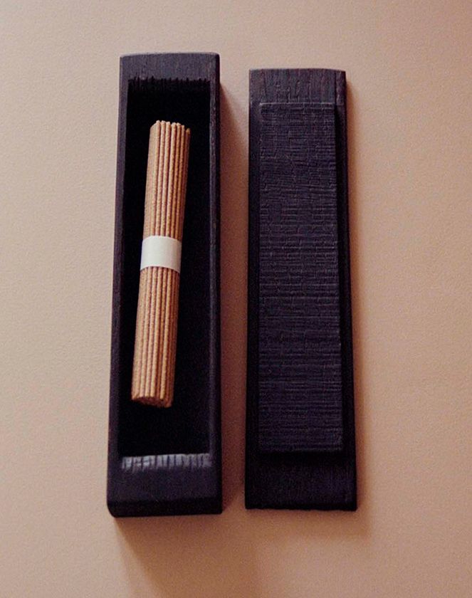 An image of an ebonised Keepsake lidded box created by woodworker Josephine Jelicich with a bundle of incense sitting inside on a brown surface