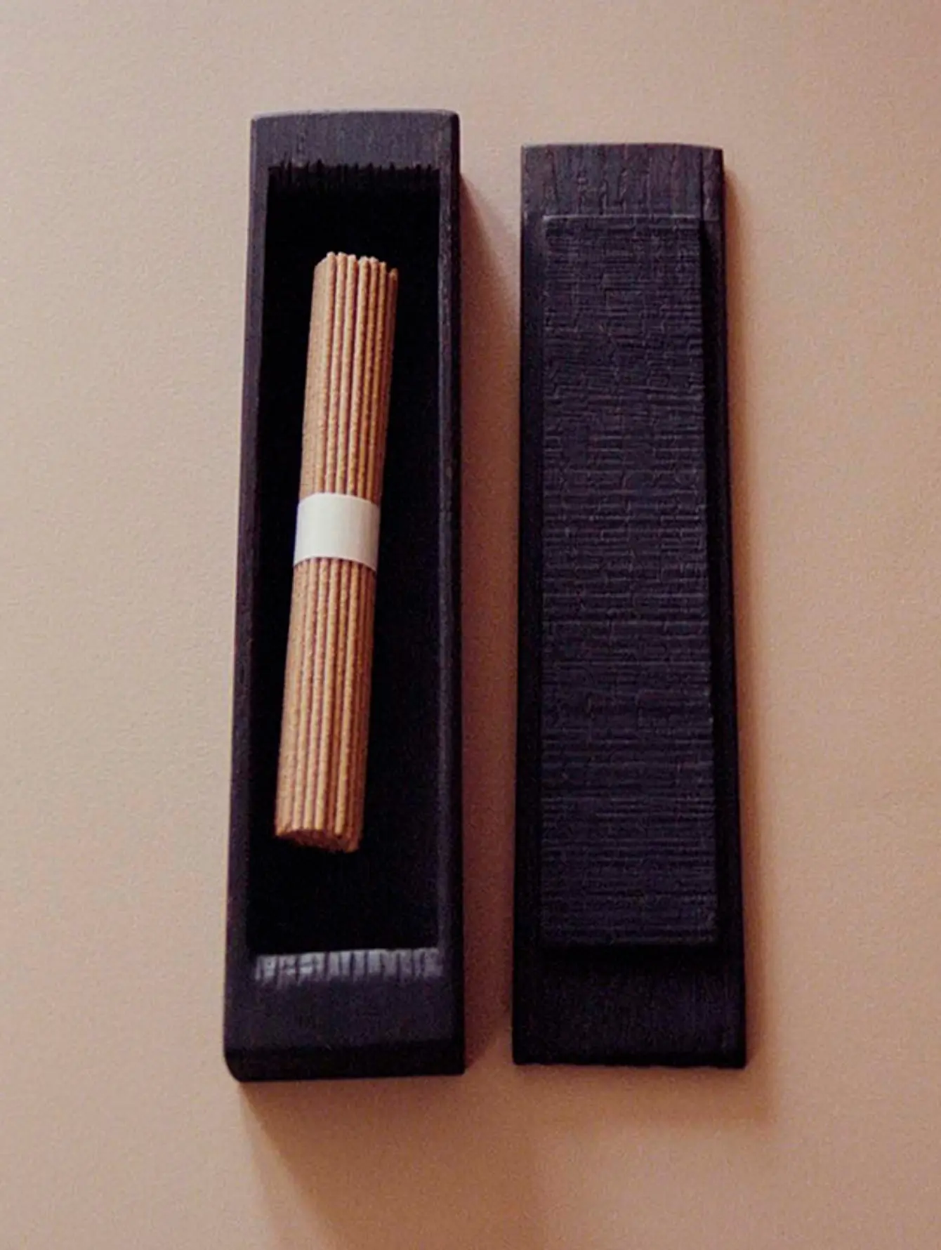 An image of an ebonised Keepsake lidded box created by woodworker Josephine Jelicich with a bundle of incense sitting inside on a brown surface