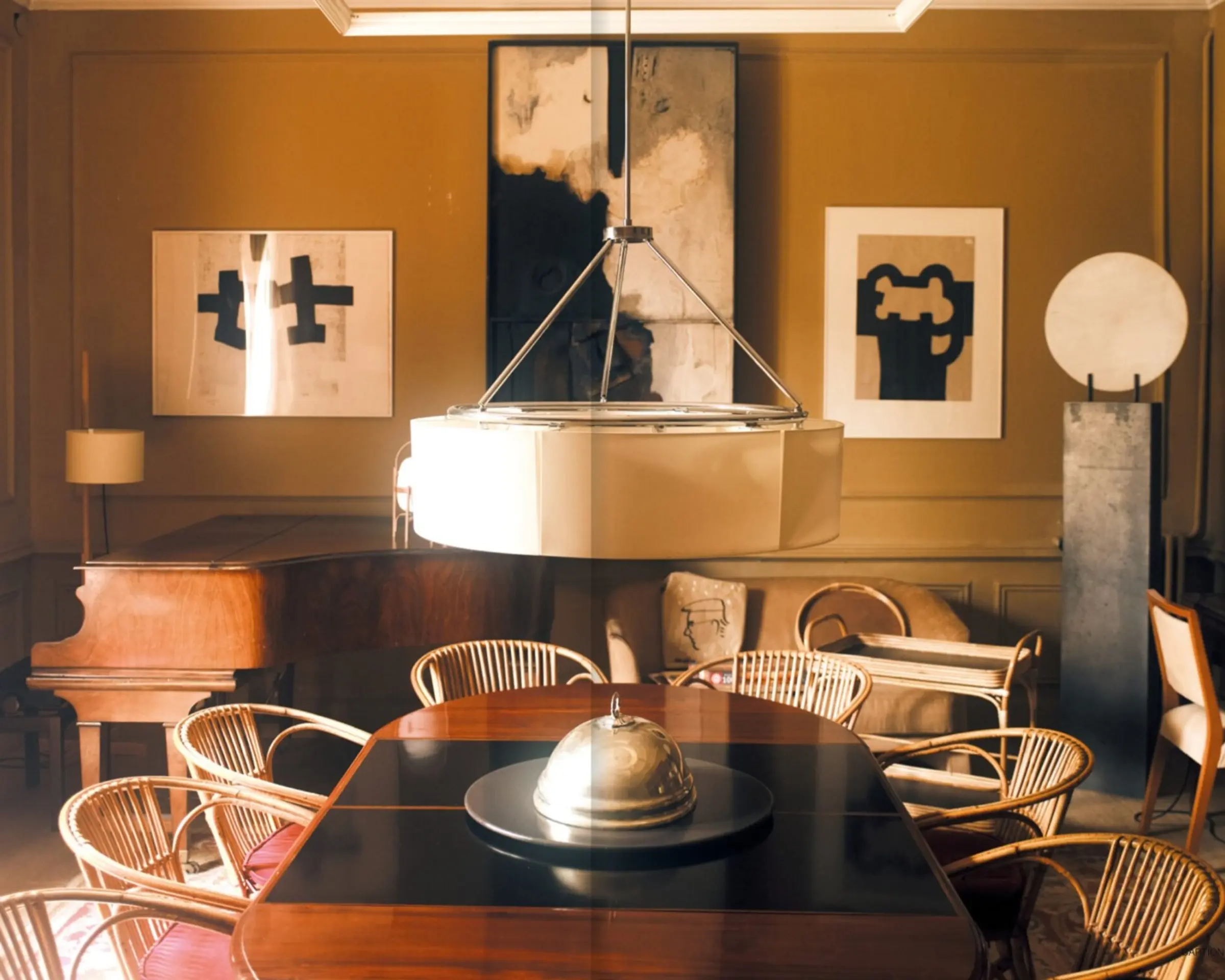 a photograph inside a dining room with a large light pendant above a dining table