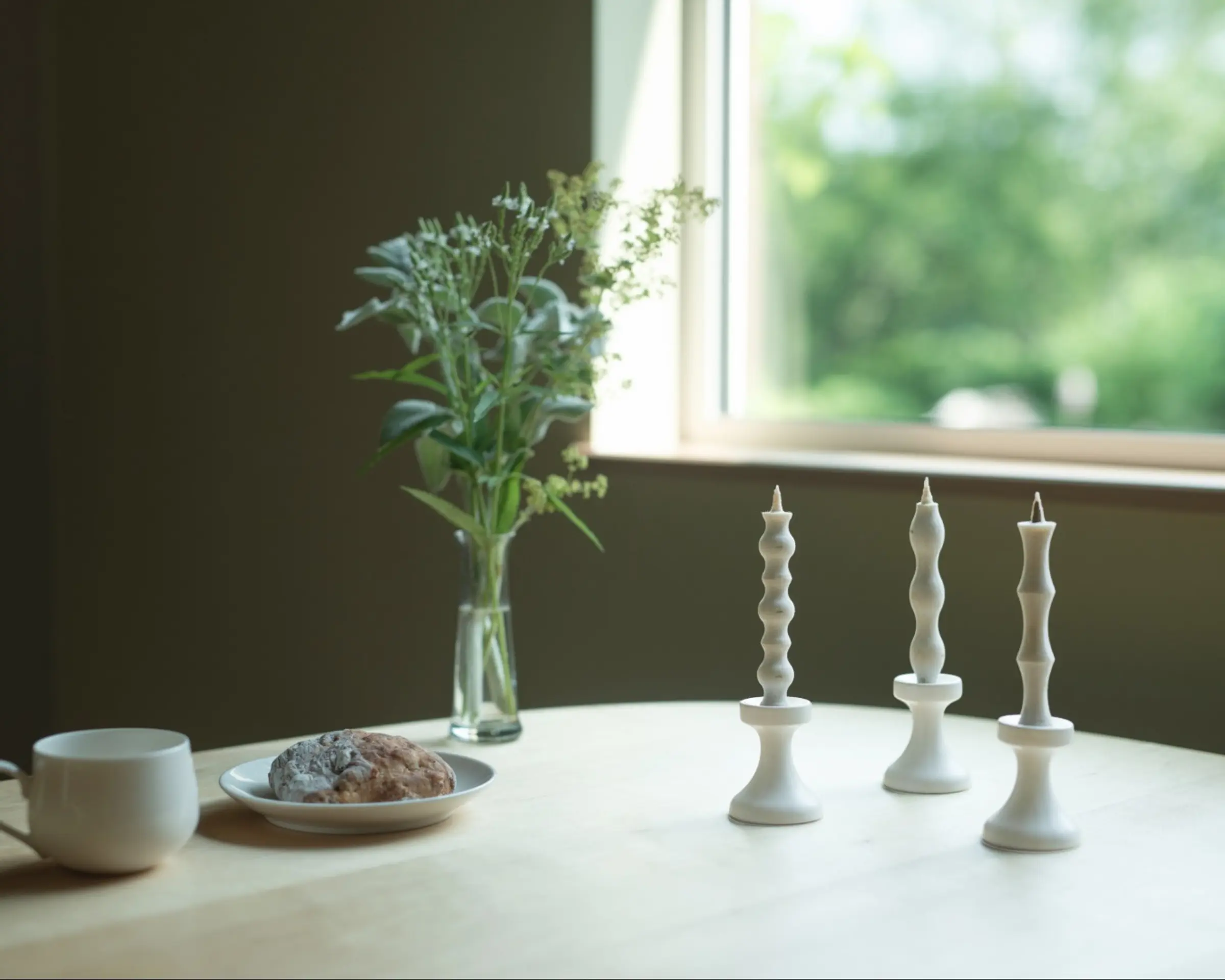 Candles in Takazawa candle holders on a dining table with a window in the background