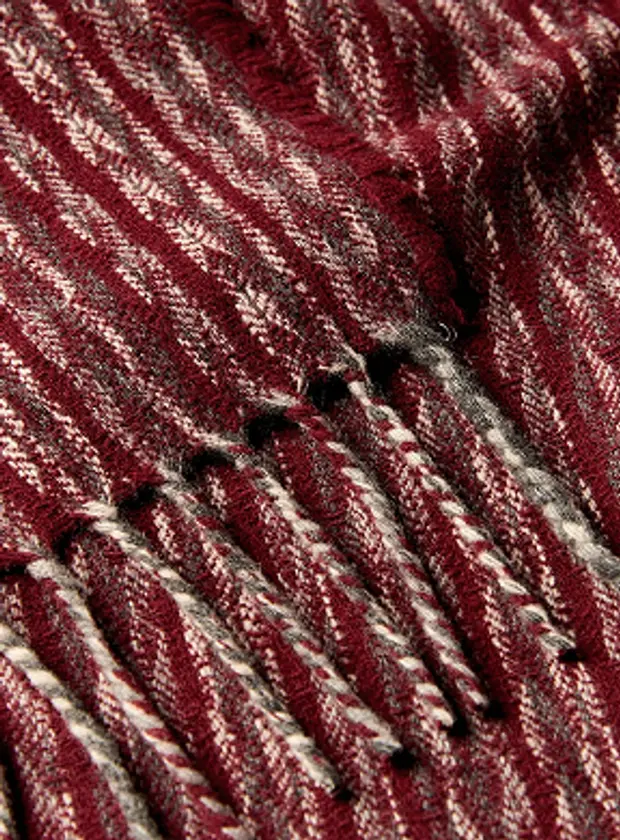 A close up detail shot of Burels Manta lumens merino wool blanket in a herringbone pattern with tones of grey cream and deep burgundy red