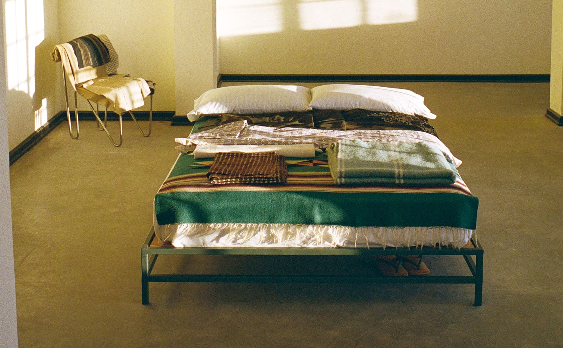 Bed layered with folded textiles and woven blankets in Donald Judd's studio apartment, photographed for Neptune Papers Issue Ten, available from Handcrafted Modern.