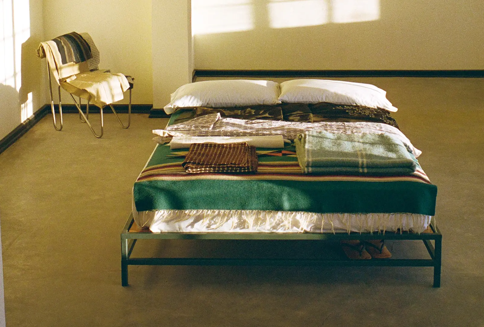 Bed layered with folded textiles and woven blankets in Donald Judd's studio apartment, photographed for Neptune Papers Issue Ten, available from Handcrafted Modern.