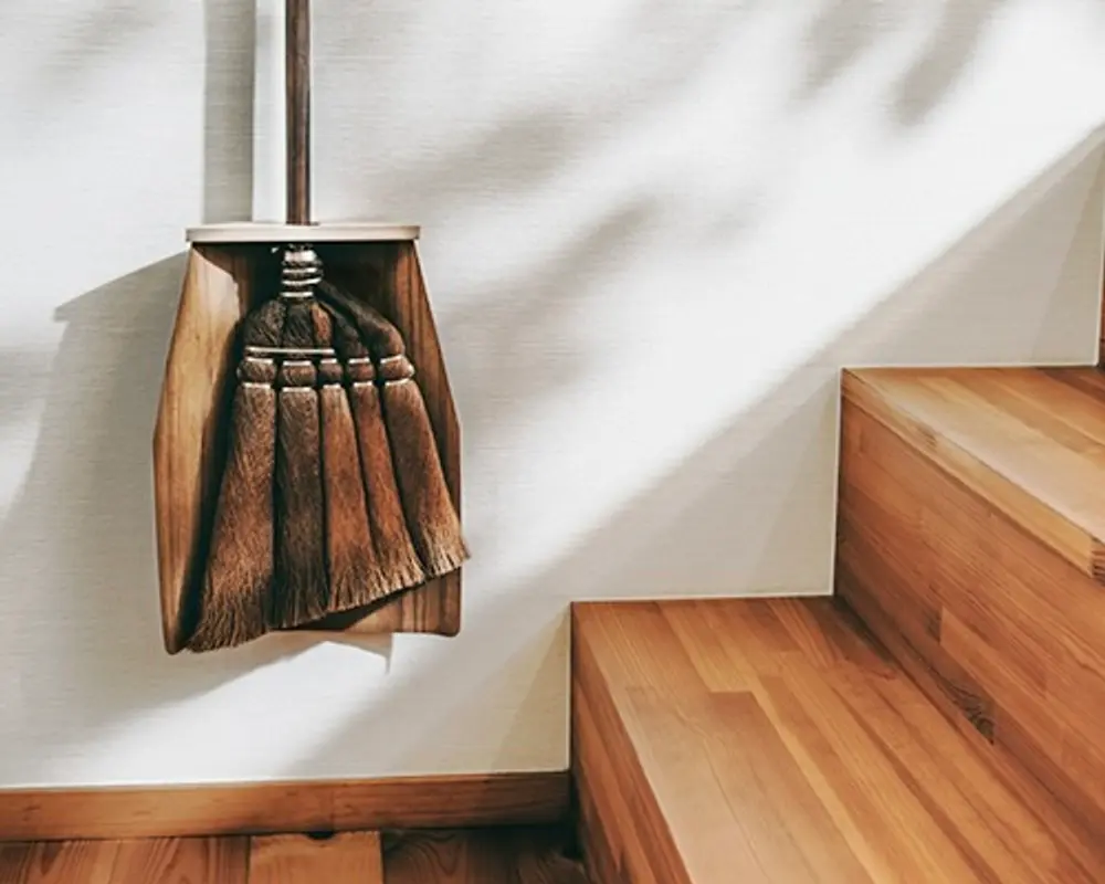 natural wood dust pan and palm fibre broom hanging in a stairwell