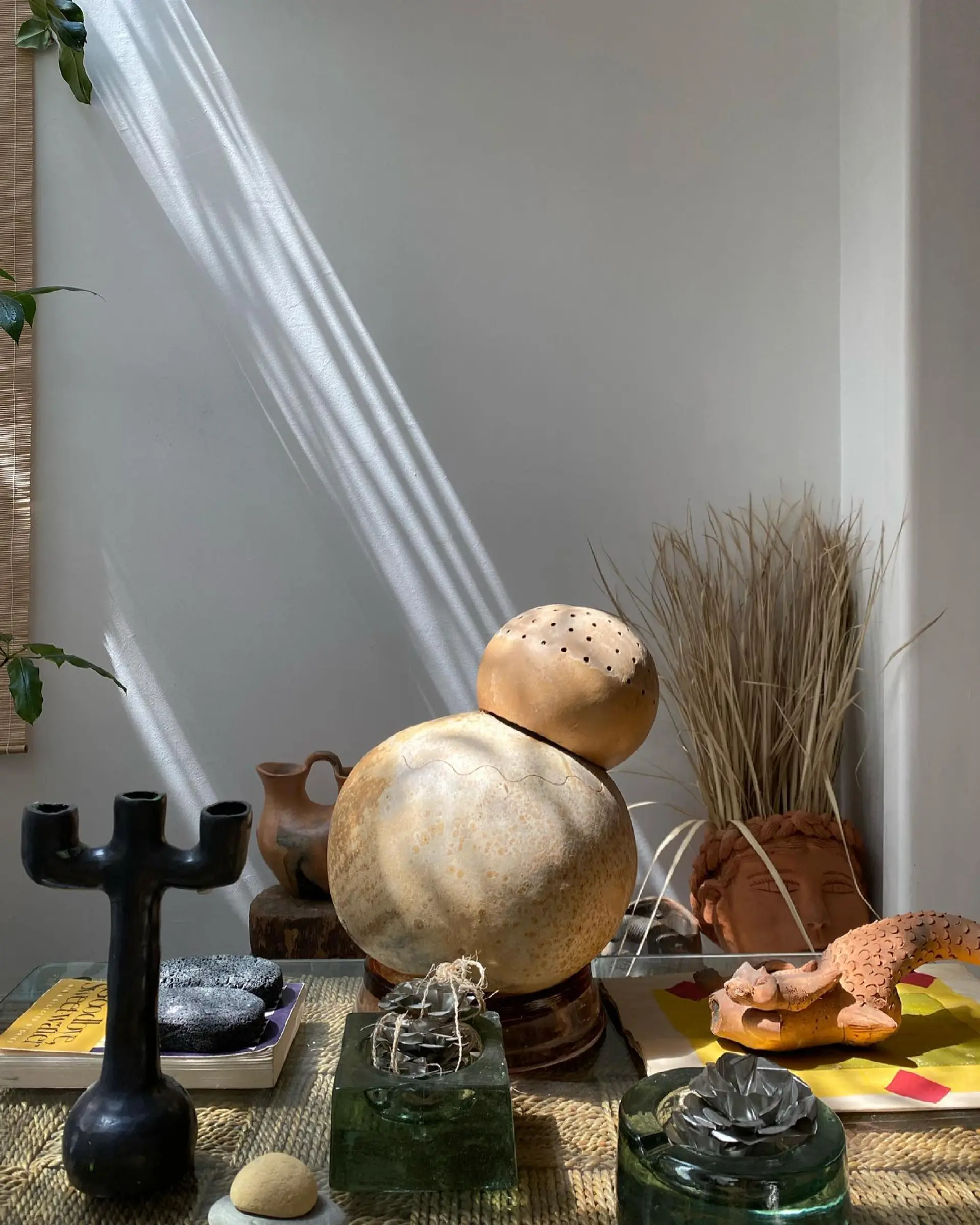Image of a table with decorative objects, pottery, glassware and a candlestick