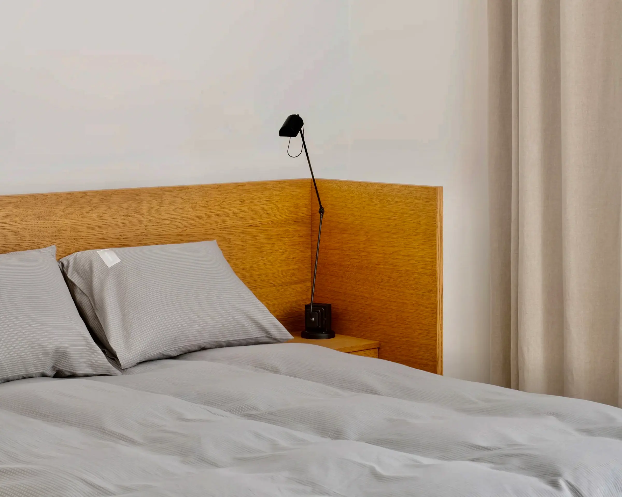 Magniberg Wall Street Oxford Pima Cotton Duvet Cover in dark Grey on a modern wooden bed frame with a bedside lamp against a white wall