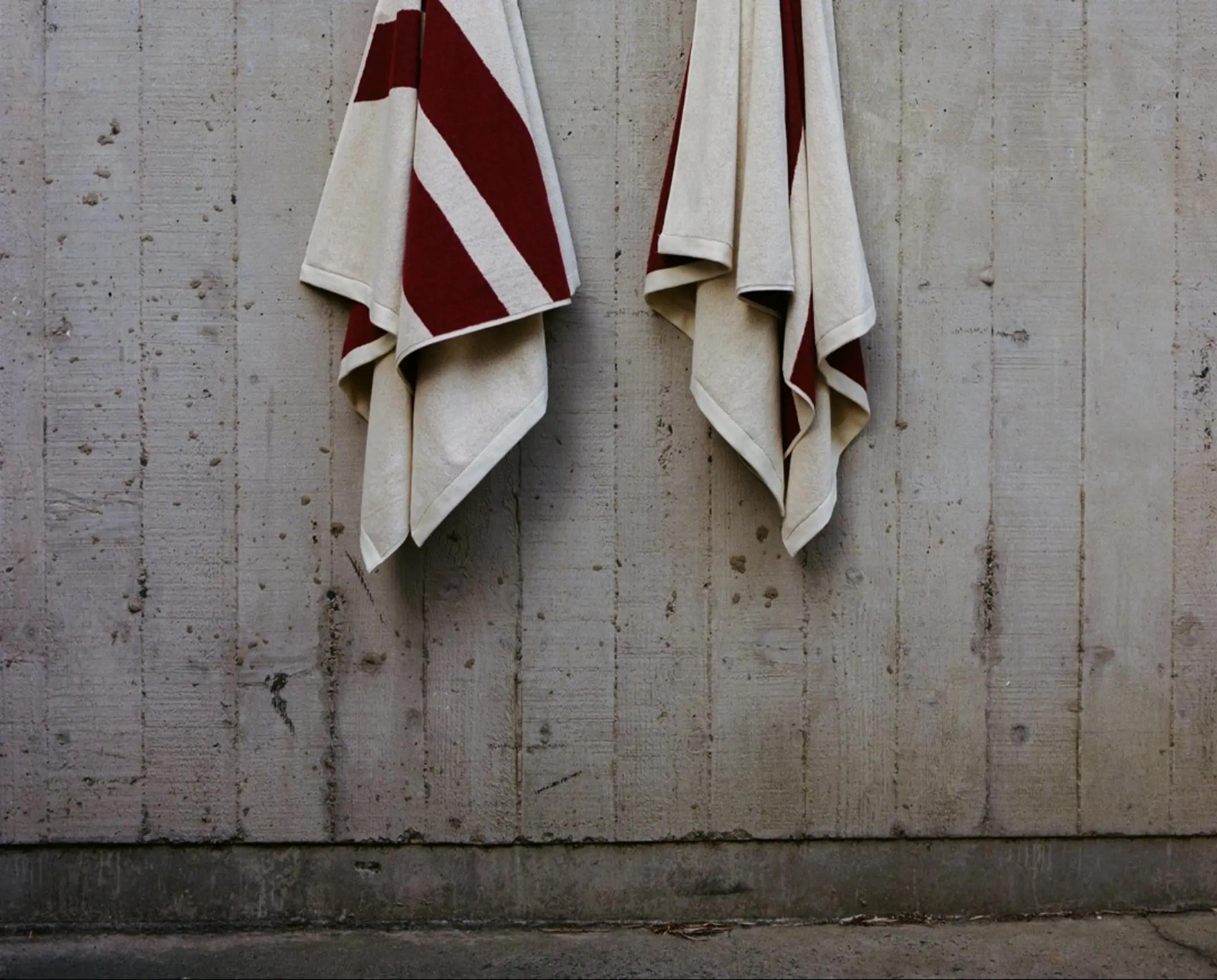 Tow pool towels hung up on a concrete wall