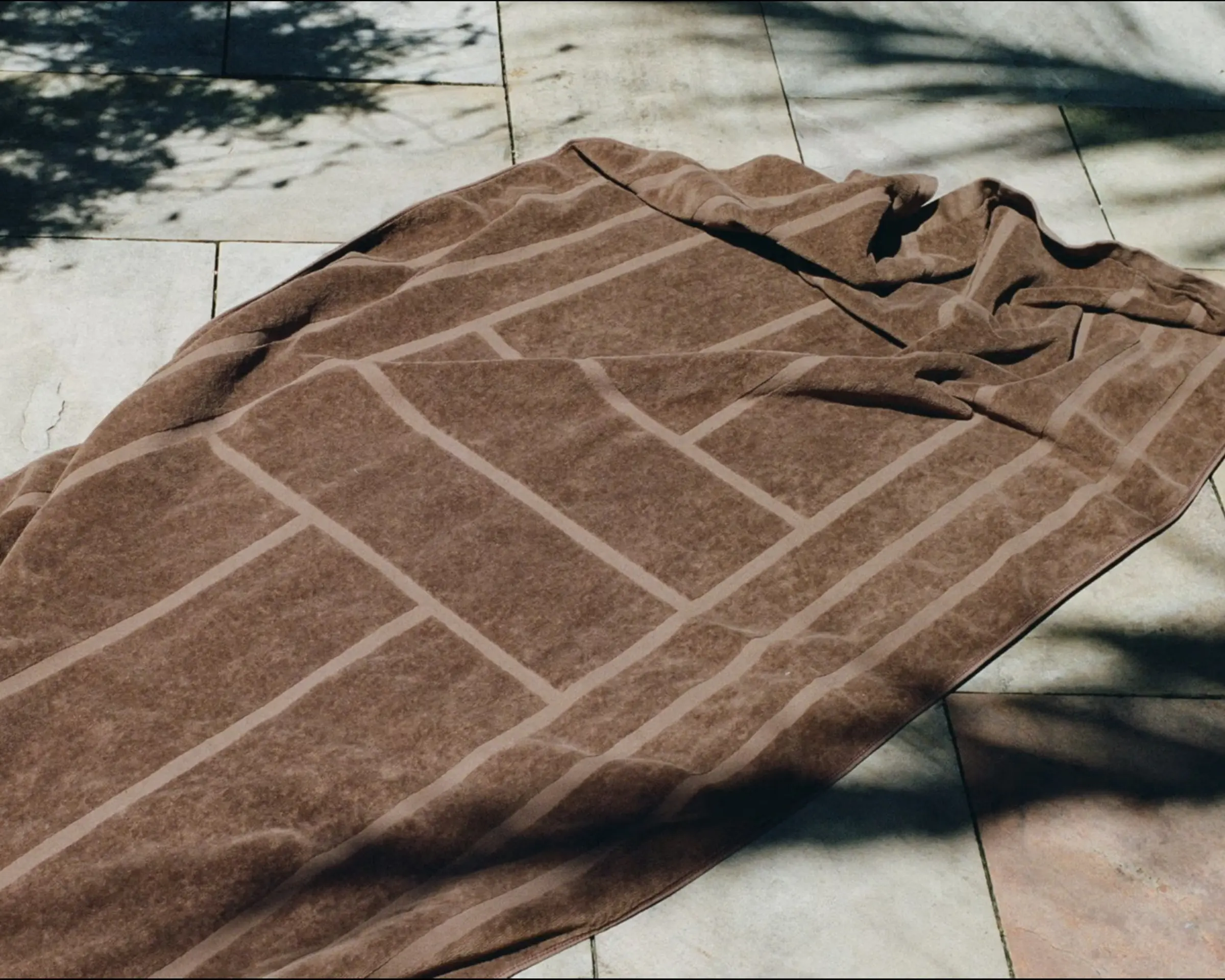 Woodford pool towel on tiles with tree shadows around it