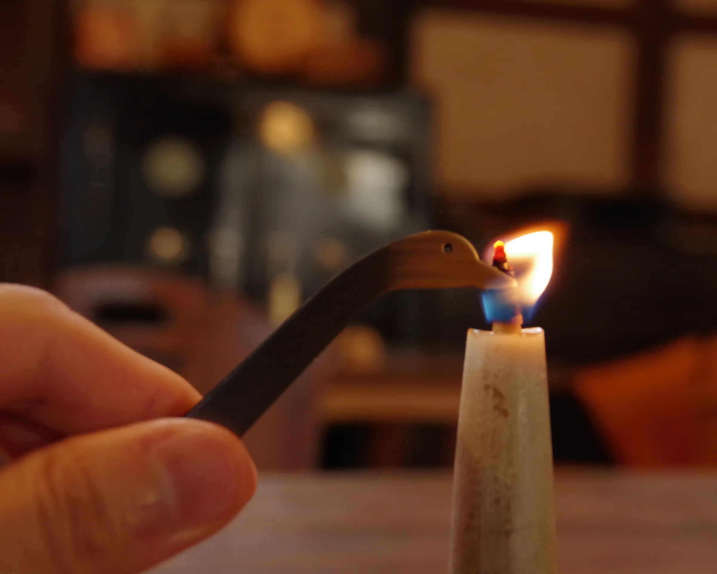 Metal duck shaped candle snuffer extinguishing a flame