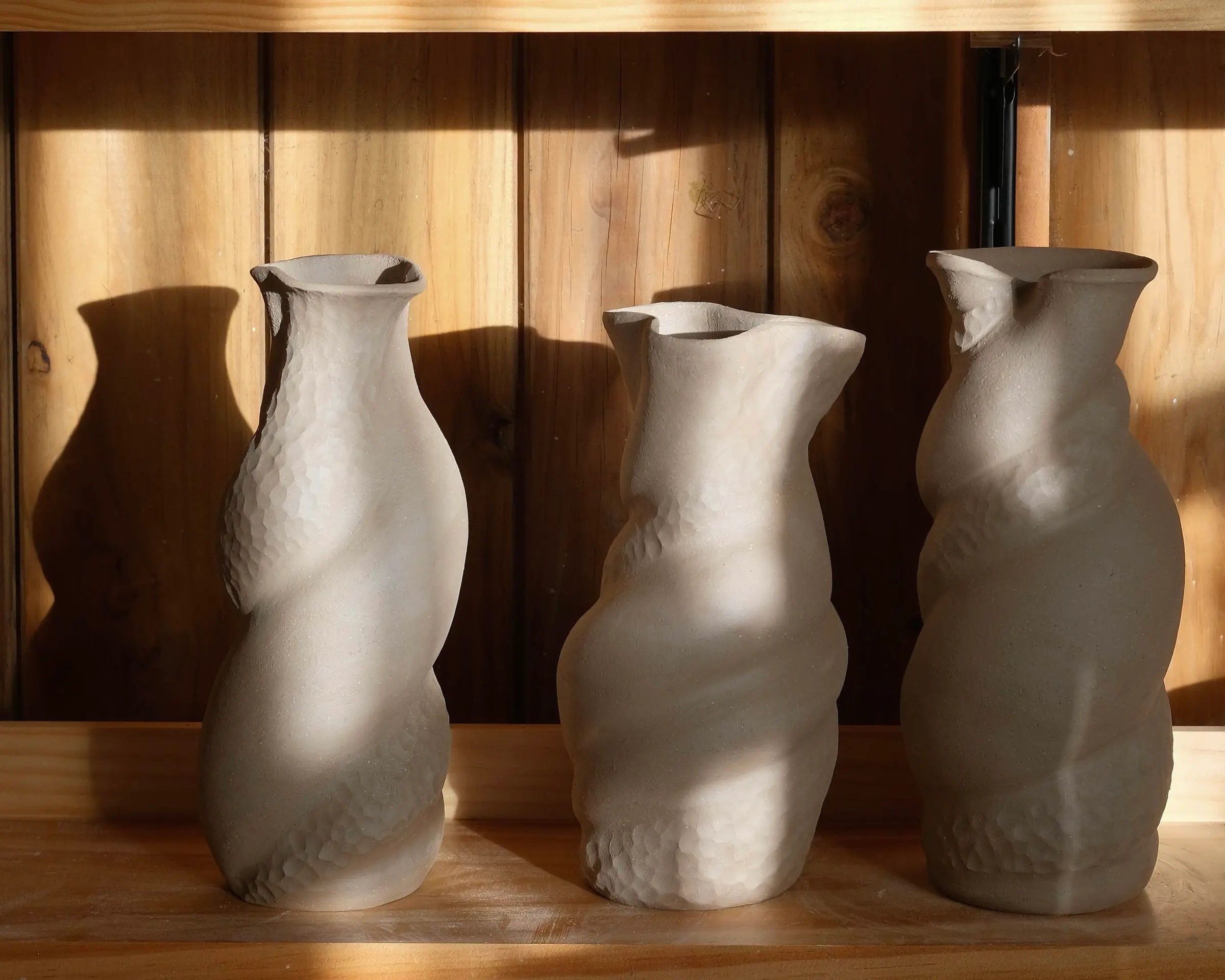 Three handmade sculptural stoneware vases by New Zealand ceramic artist Kaiqi Qiu, displayed in sunlight in her Grey Lynn studio.