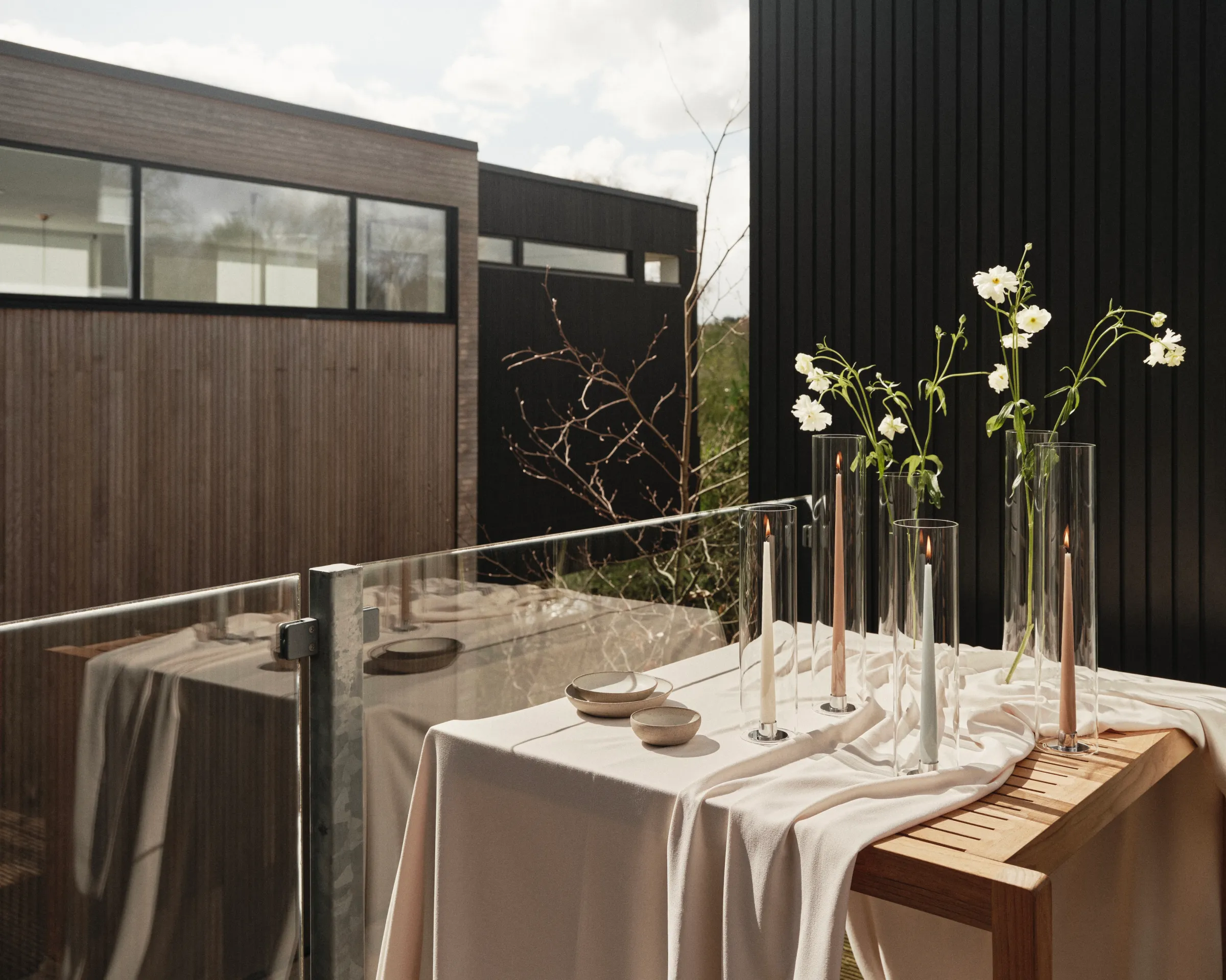 an outdoor setting of ester and Erik hand dipped candles on a wooden table with a white tablecloth and flowers