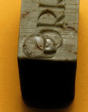 An image of Orris soap, green with flecks sitting on a yellow background