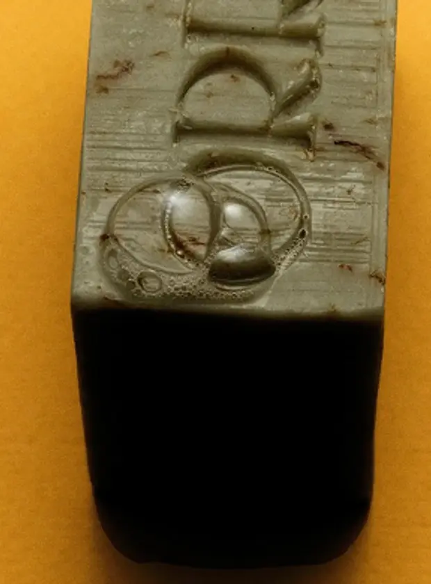 An image of Orris soap, green with flecks sitting on a yellow background