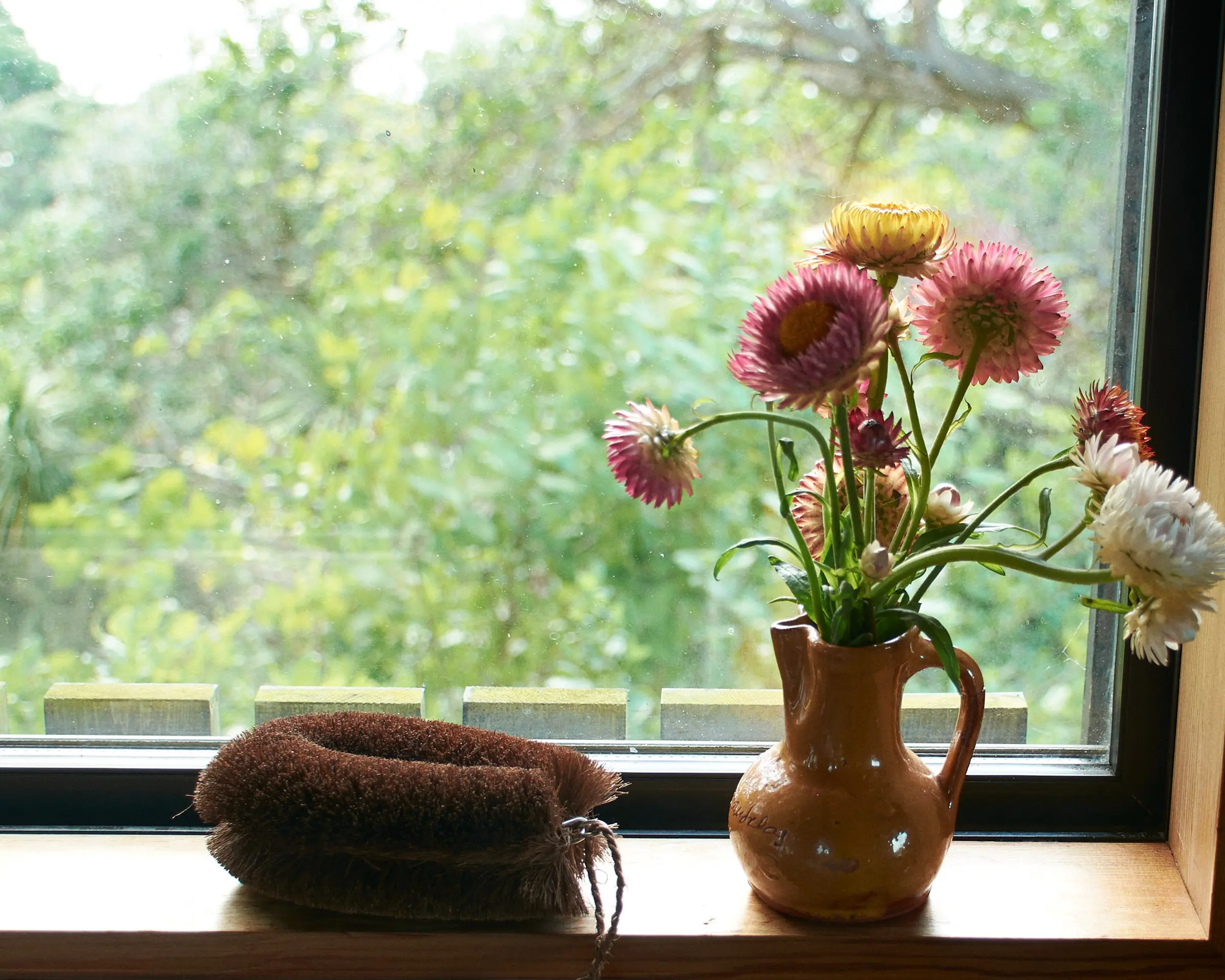 tawashi brush on a windowsill by a vase with flowers