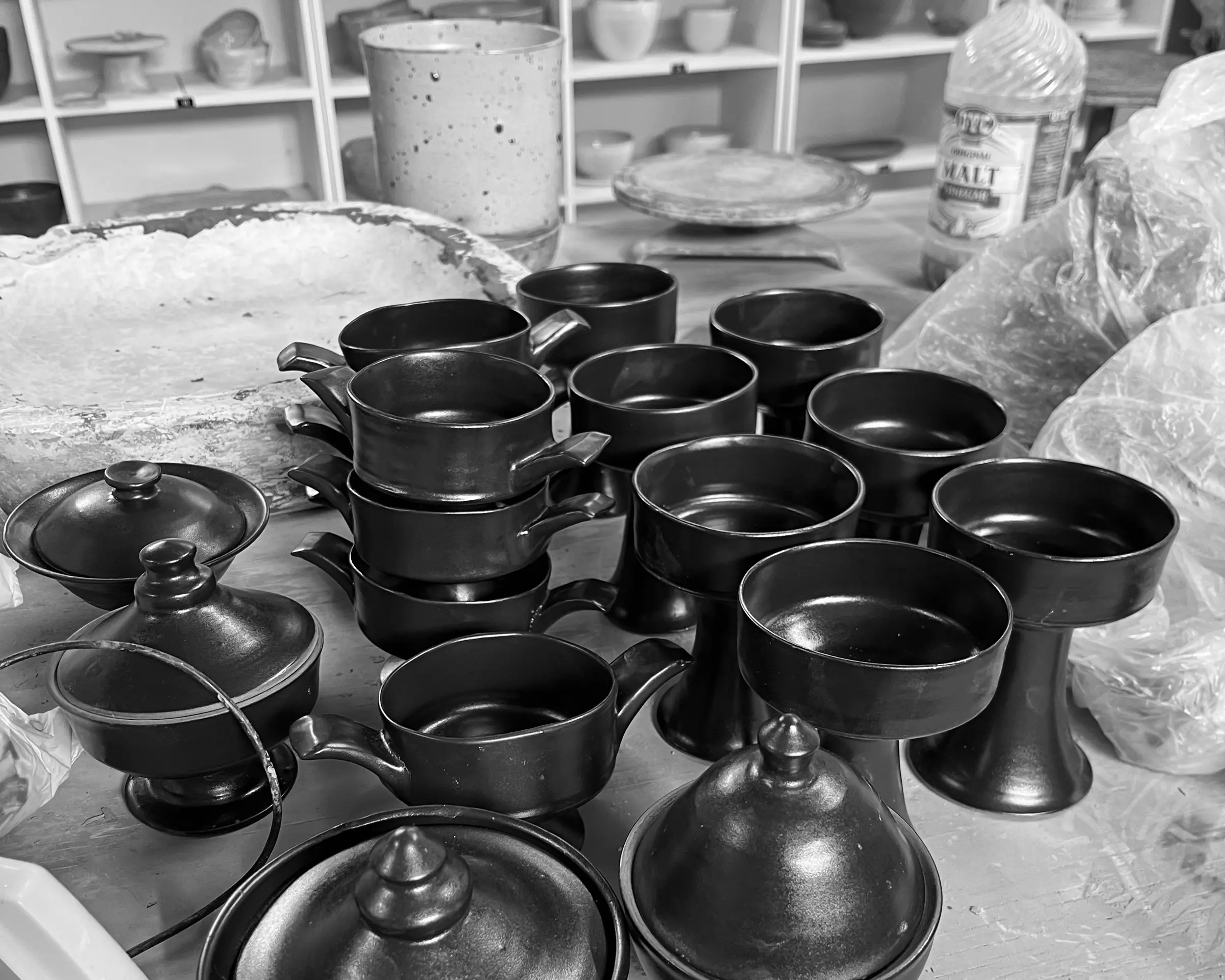 black and white image of Kirsten dryburghs blackware collection of ceramic vessels- cups, chalice, lidded bowls