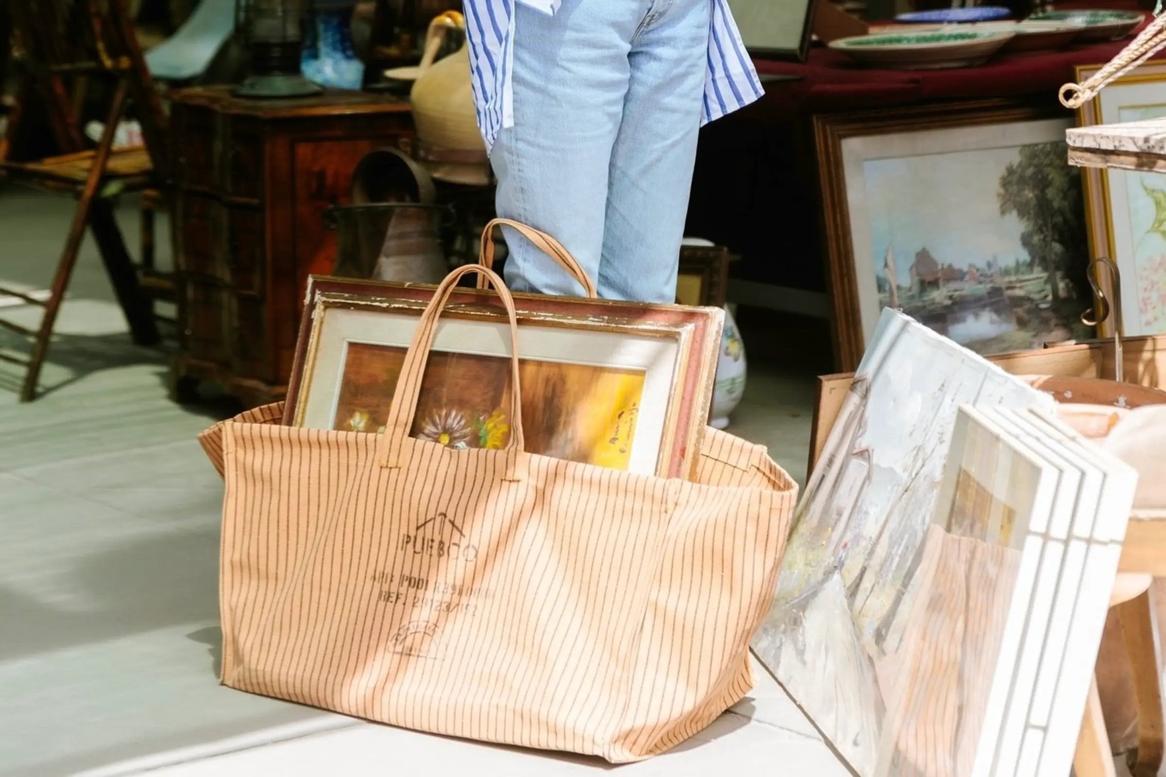 a Puebco waxed cotton large tote bag carrying a painting in a market