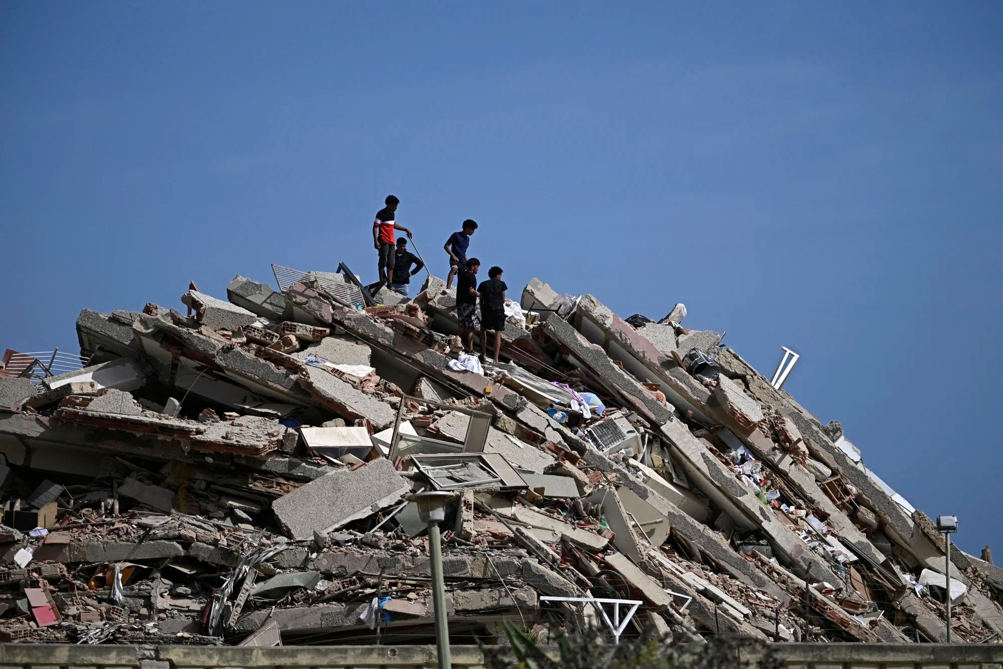 People search for survivors while others try to salvage belongings in a collapsed building following an earthquake in Catia La Mar, La Guaira state, some 30km north-west of Caracas, on June 25, 2026. (Photo by Federico PARRA / AFP)