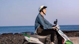 Leon Hong rides an electrity scooter by the sea