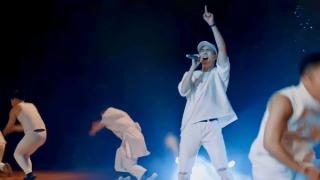 Leon Hong singing with ensemble dancers on a modern stage