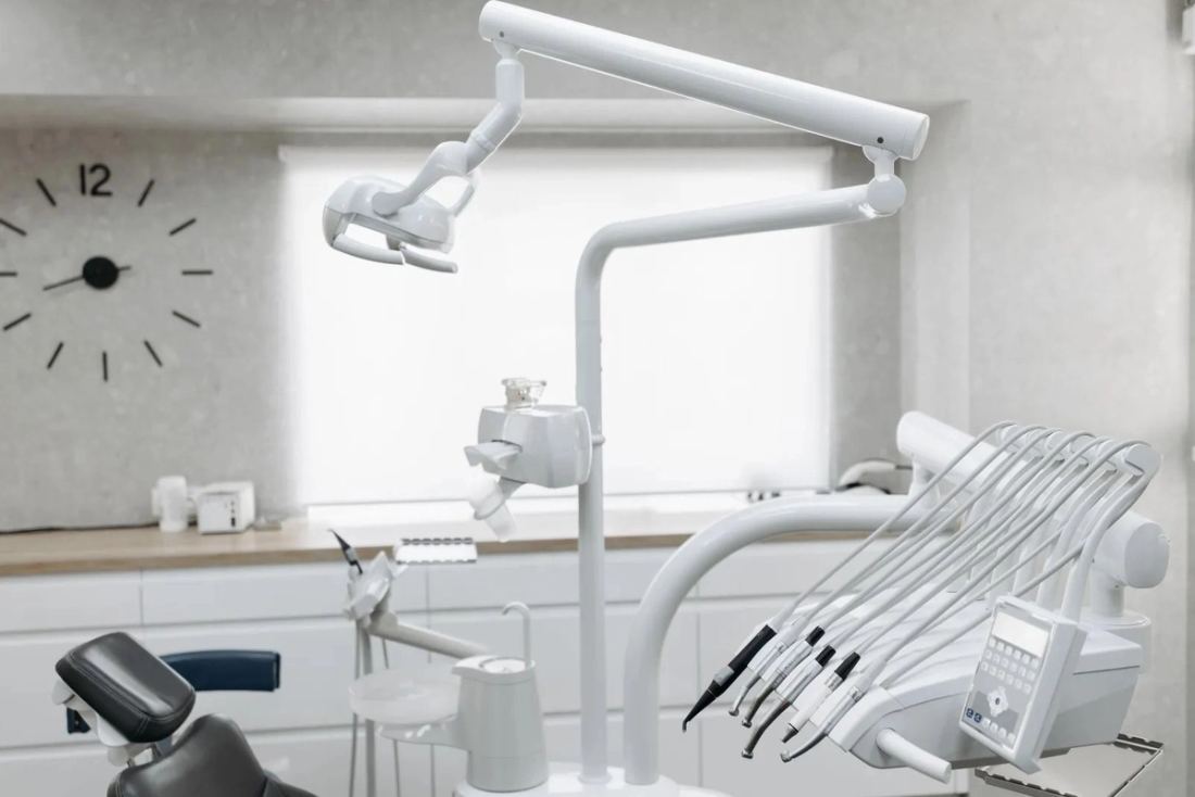 A bright, empty treatment room with the lamp and handpieces at rest.