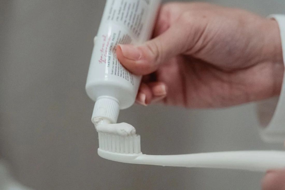 Toothpaste being squeezed onto a toothbrush.