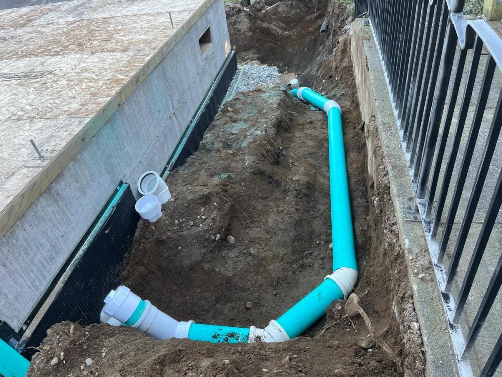 Rigid PVC foundation drain routed around a new home in Seattle