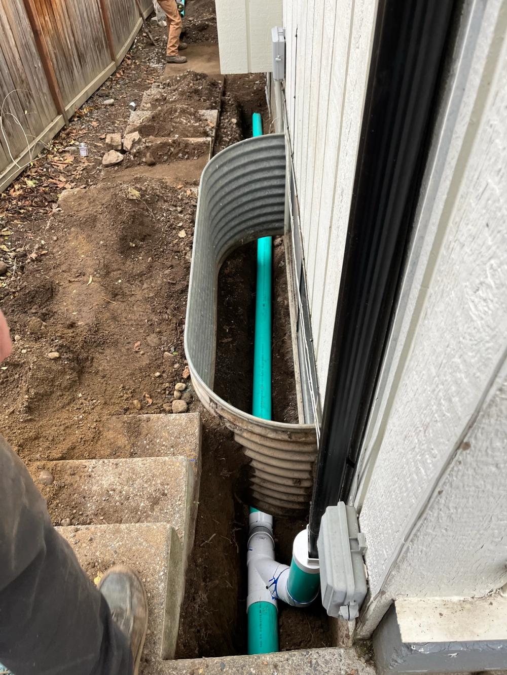 PVC drain line run past a basement window well in Anacortes