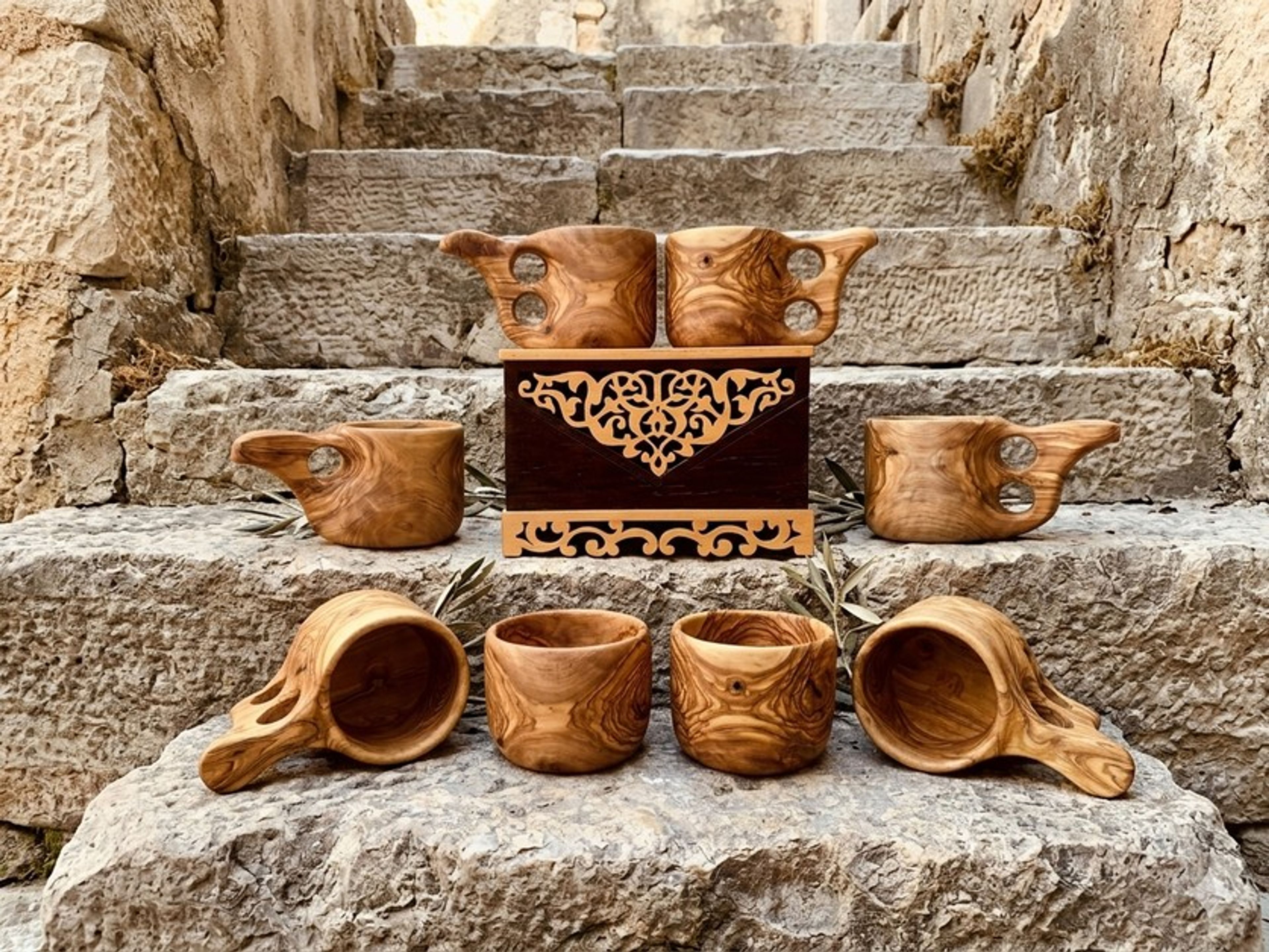 Taş basamaklar üzerinde zeytin ağacından oyma bardaklar ve tütsülük