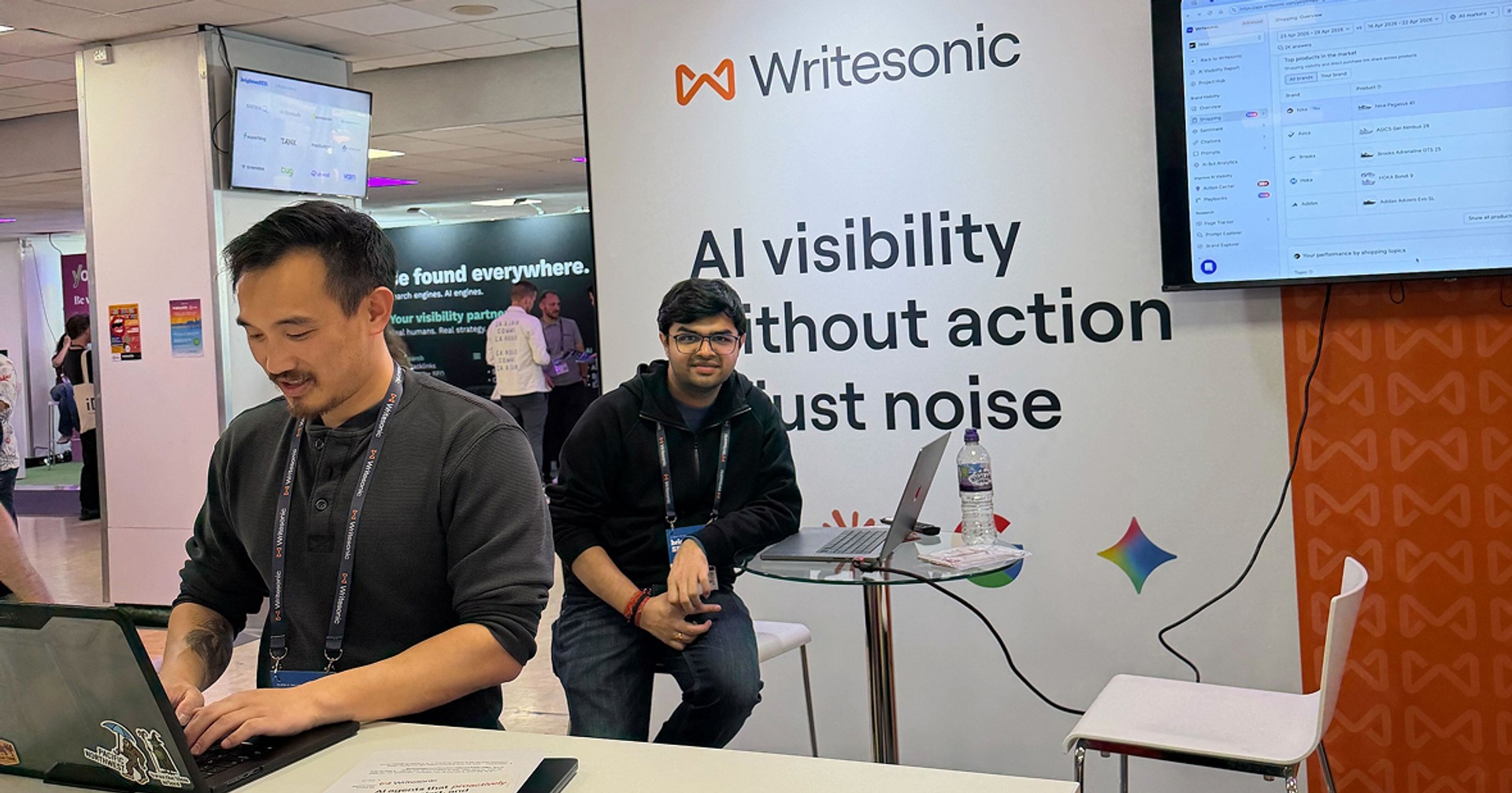 The Writesonic team at our booth at brightonSEO, with the product on screen