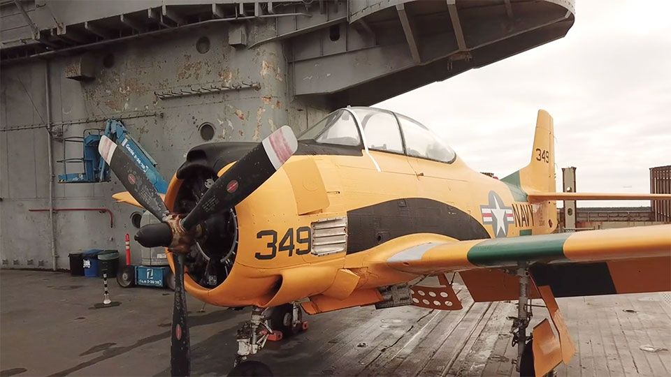 on the deck of an aircraft carrier, viewing a World War 2 aircraft bright yellow