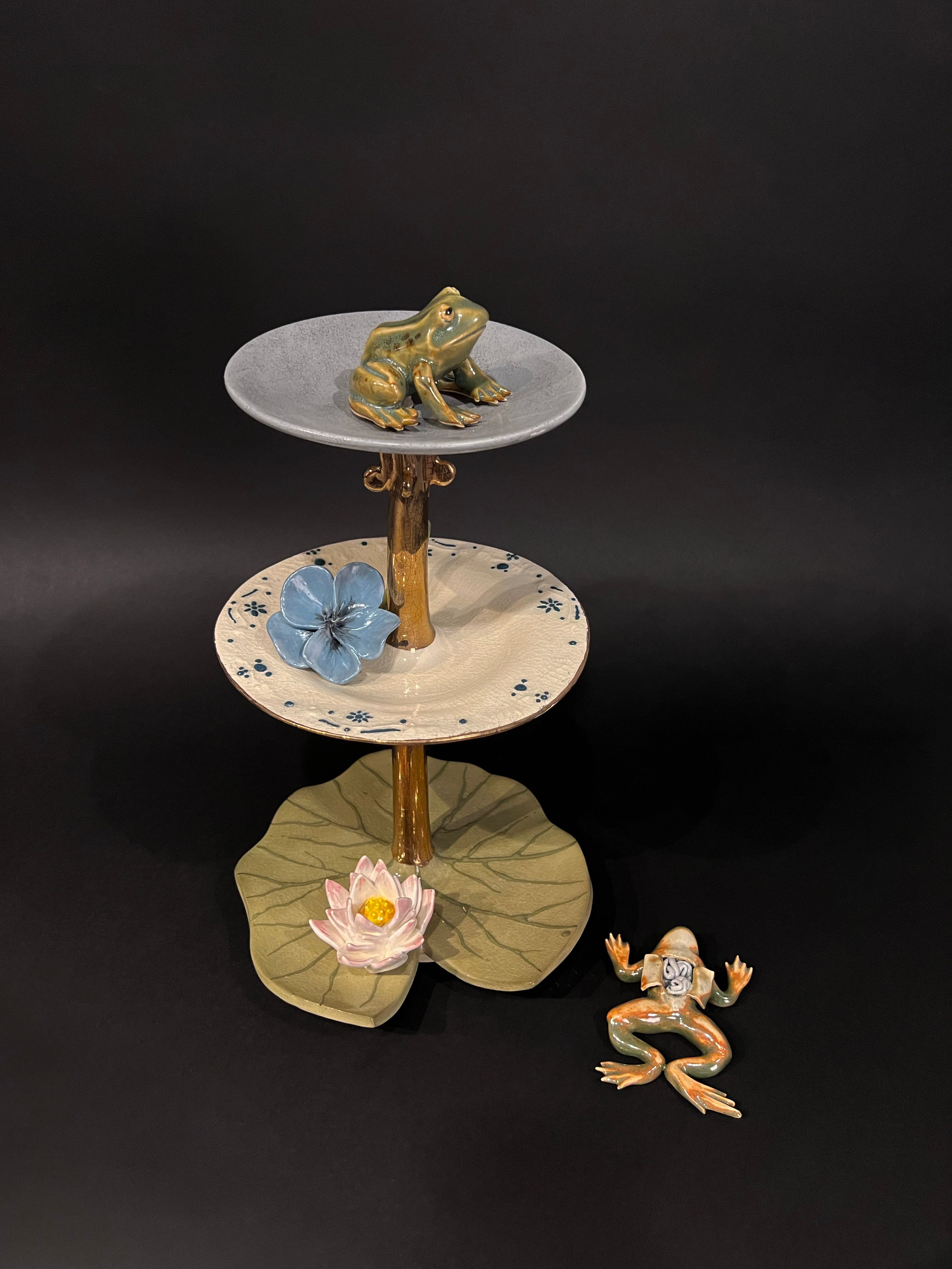 ceramic and glazed sculpture made from hand dyed porcelain. The tiers of these frogs' world are meant to look like a victorian tea tray, insinuating that their plight is merely for our entertainment or acquisition of knowledge. 