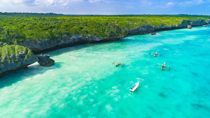Aerial view of turquoise waters and traditional outrigger boats off the coast of Zanzibar, Tanzania.